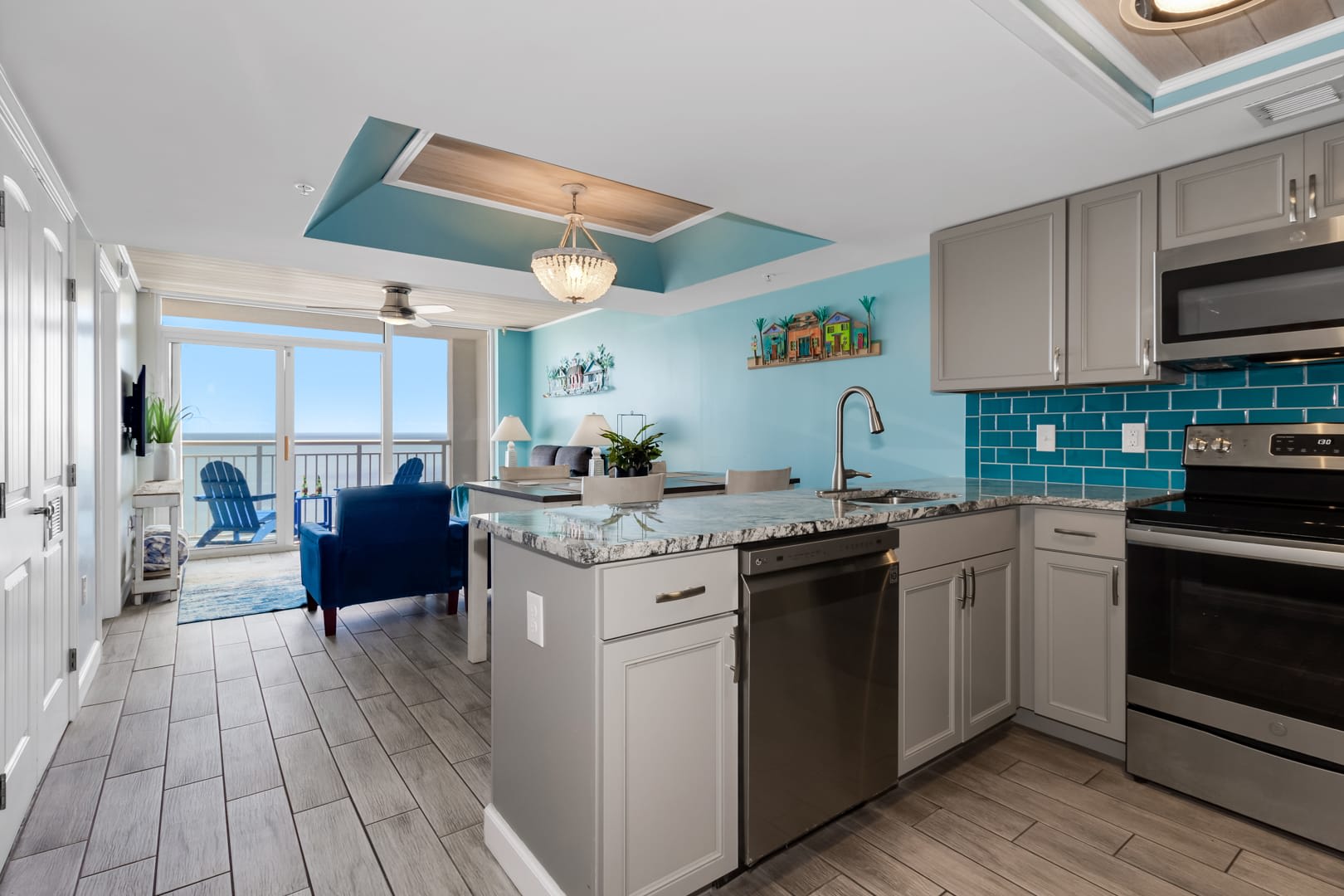Cook and entertain in style with this open-concept kitchen featuring sleek stainless steel appliances, granite countertops, and vibrant coastal accents. Overlooking the living area and balcony, it's perfect for enjoying meals with ocean views.