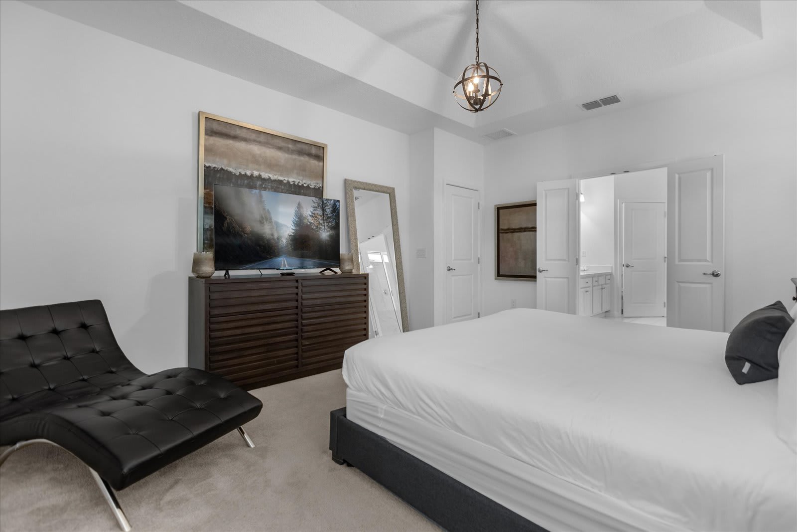 Spacious Queen Bedroom Featuring A Comfortable Seating Area And Smart TV
