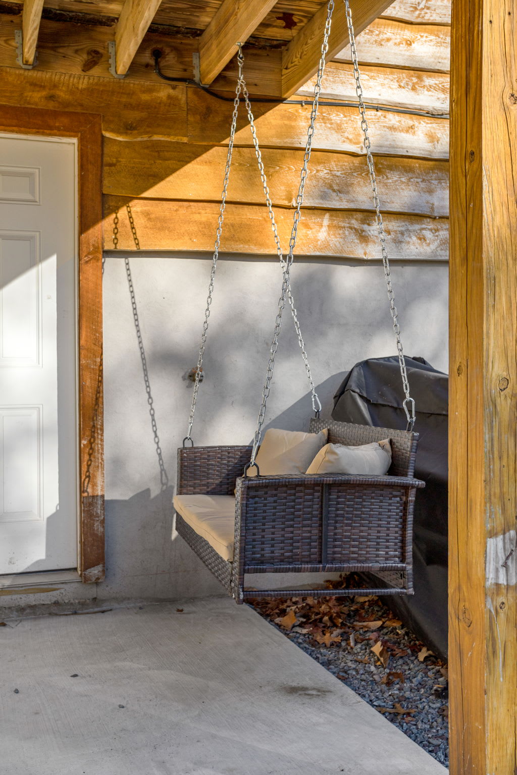 A cozy swing with plush cushions adds the perfect touch to this shaded outdoor space, ideal for lazy afternoons.