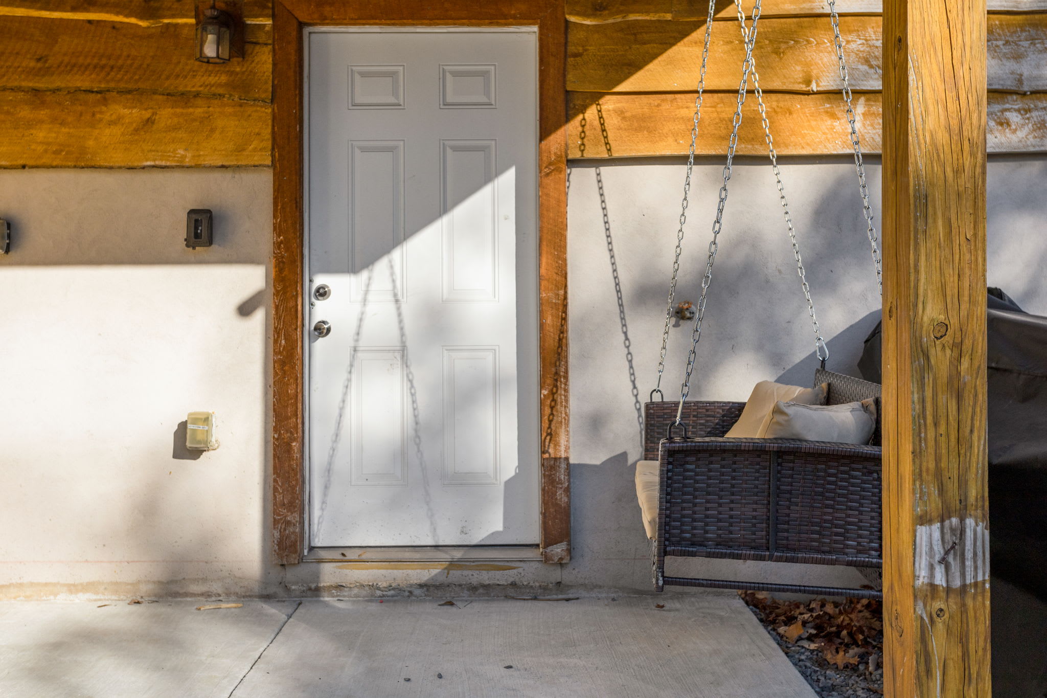 This cozy entryway features a charming swing, perfect for relaxing in the shade and enjoying the fresh air.