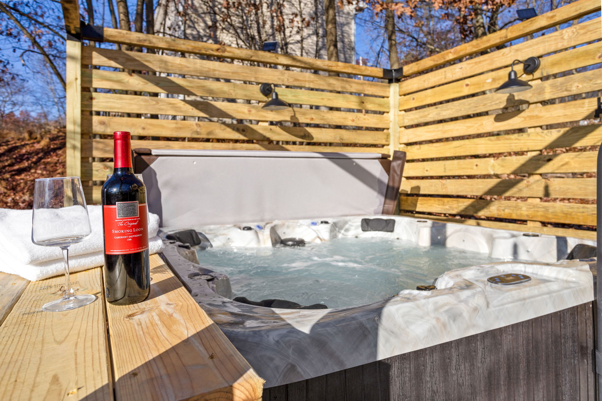 A glass of wine, bubbling jets, and warm wooden privacy walls make this hot tub the ultimate relaxation spot.