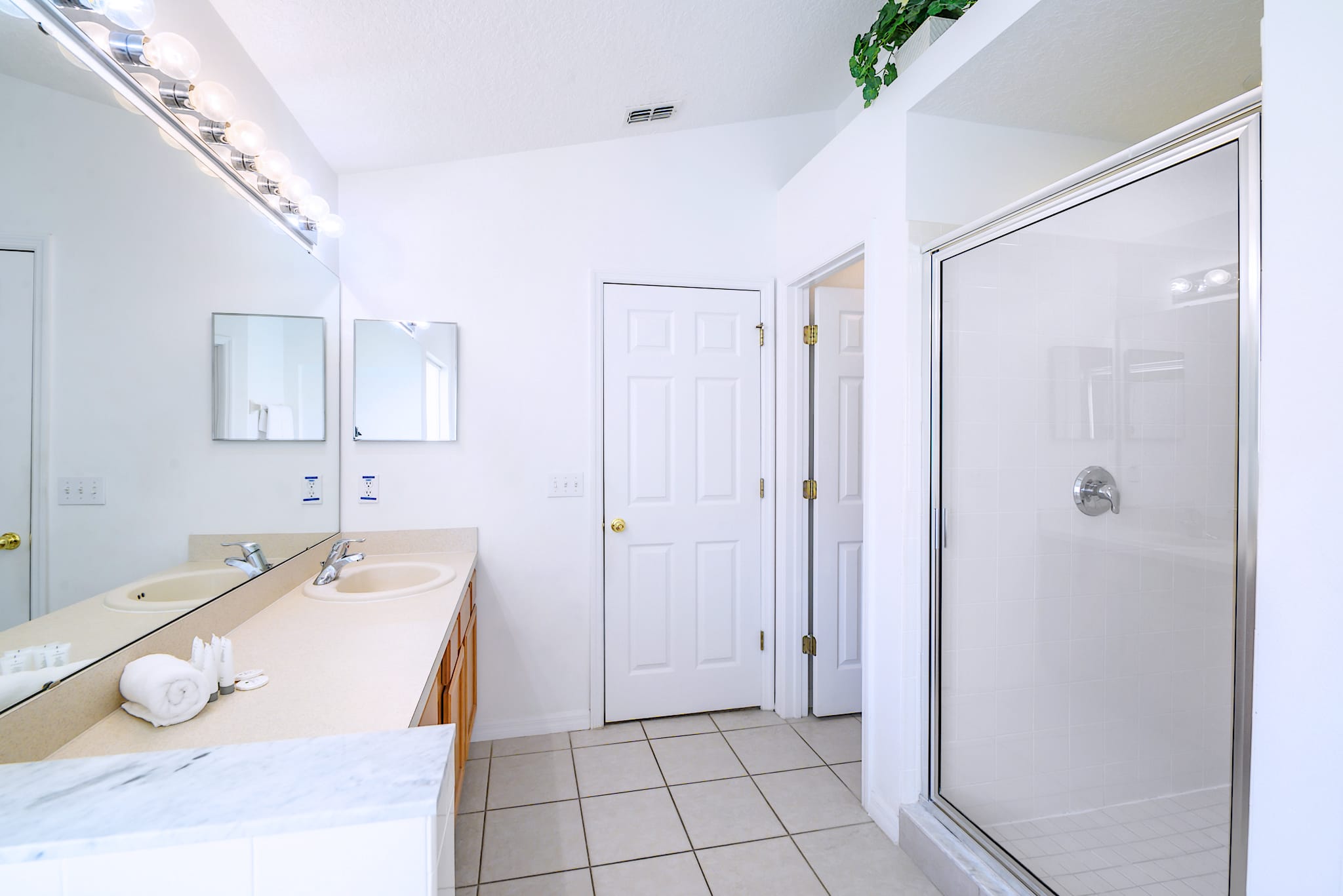 Bright Bathroom Featuring Dual Vanities And A Glass-Enclosed Walk-In Shower