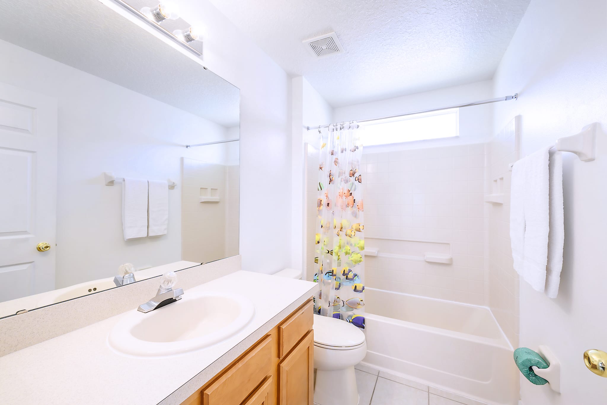 Bright Bathroom Featuring Dual Vanities And A Glass-Enclosed Walk-In Shower