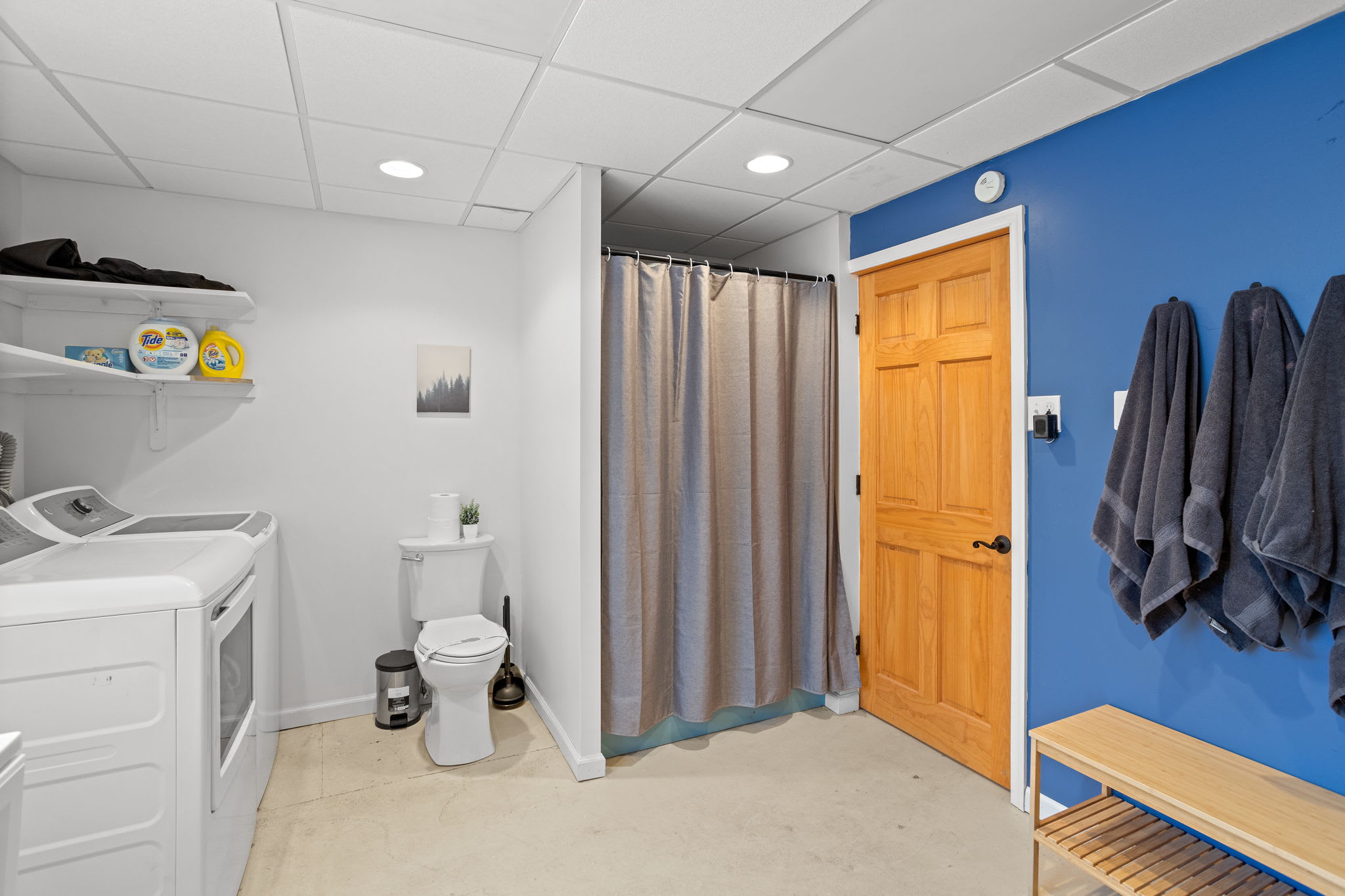 A bright and welcoming entryway featuring hooks for coats, a bench for easy shoe changes, and a stylish blue accent wall.