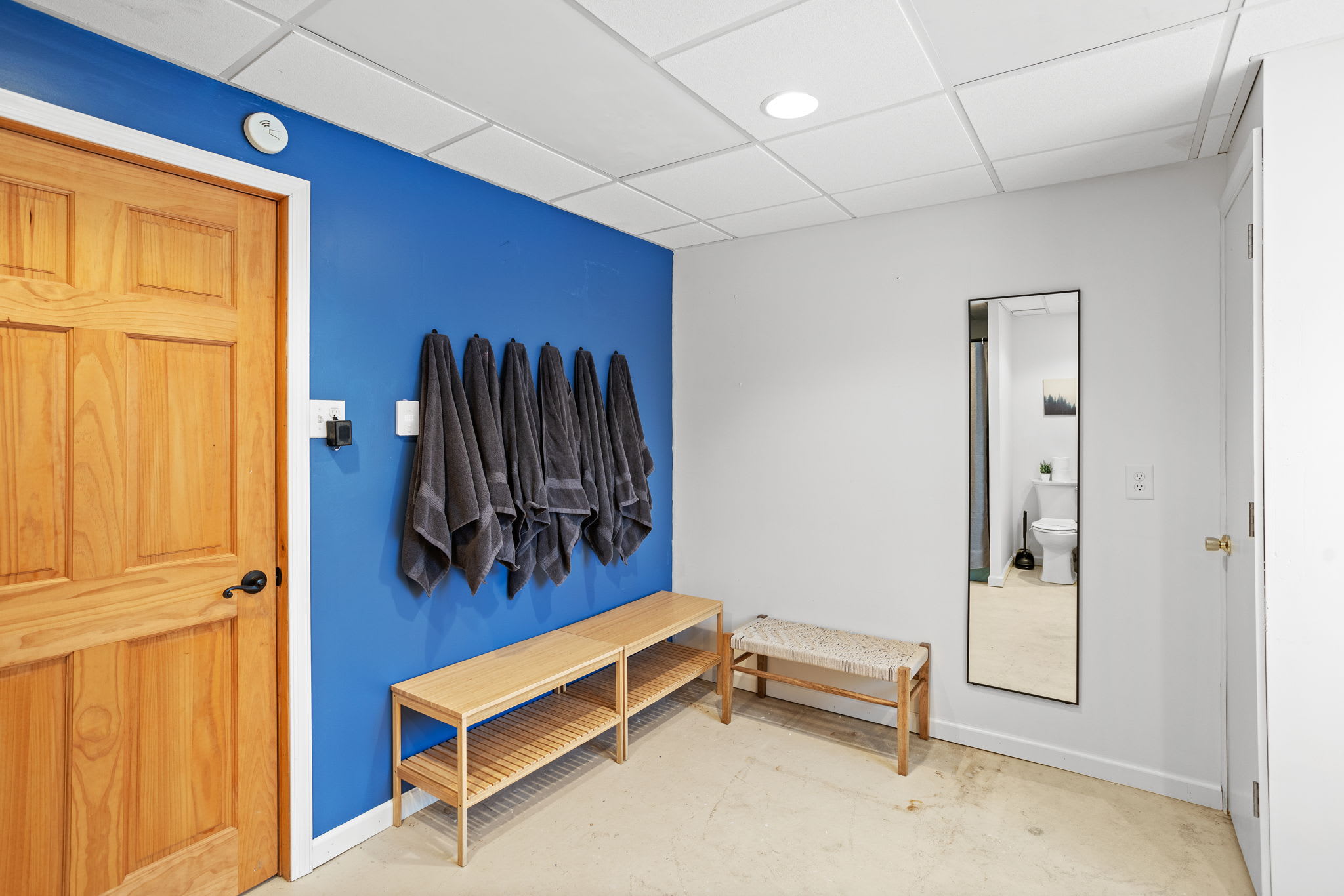 A thoughtfully designed mudroom with ample storage, sleek towel hooks, and a full-length mirror to check your look before heading out.