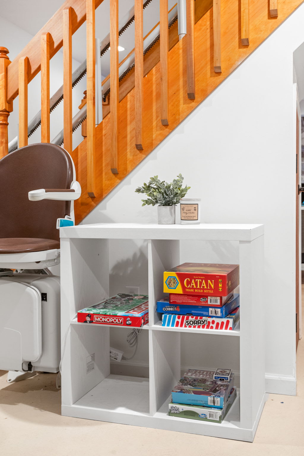 A simple yet functional storage space under the stairs, stocked with books and board games for a relaxed evening indoors.