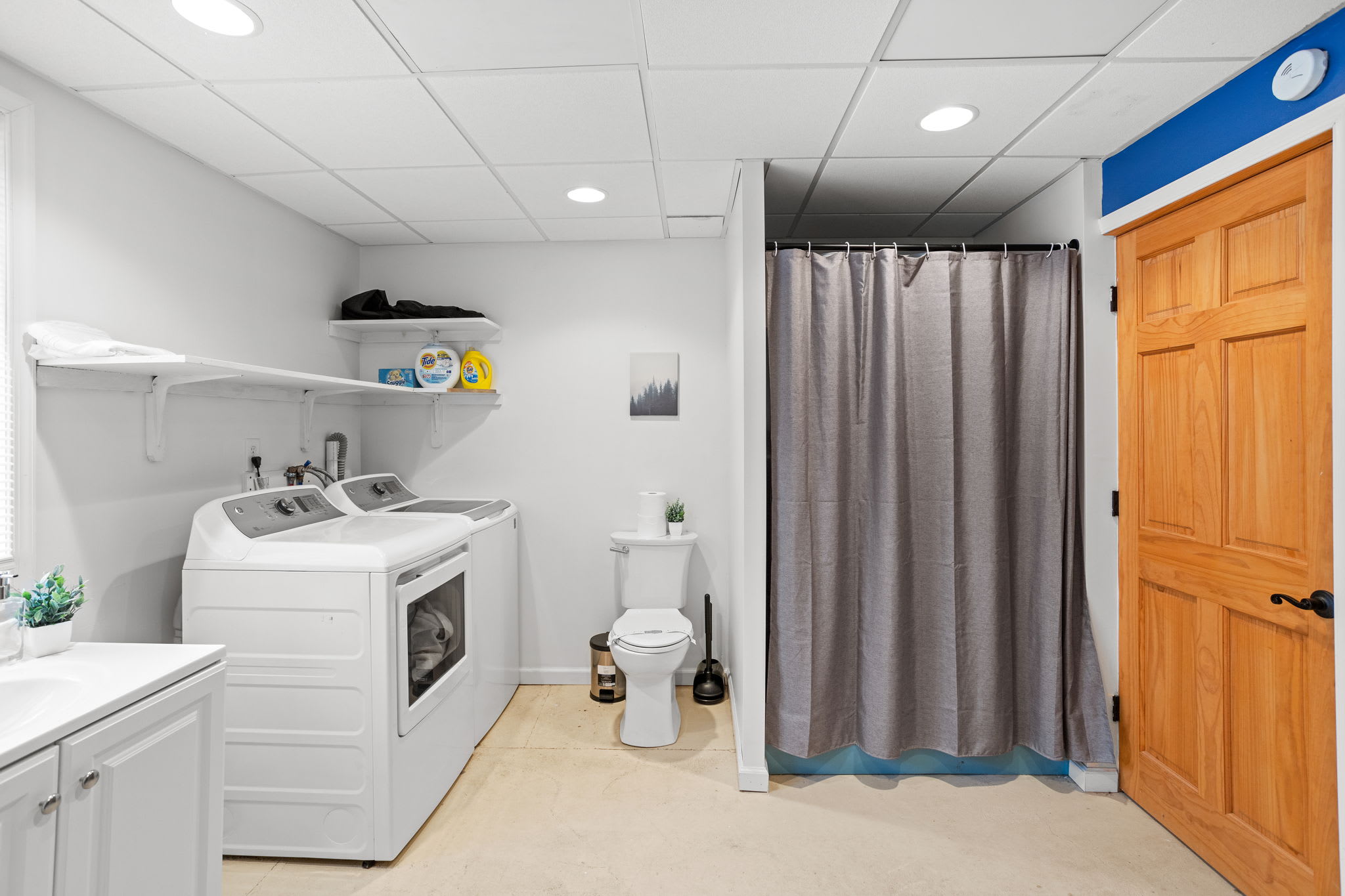 A fully equipped laundry space with modern appliances, storage, and a private shower area for added convenience.