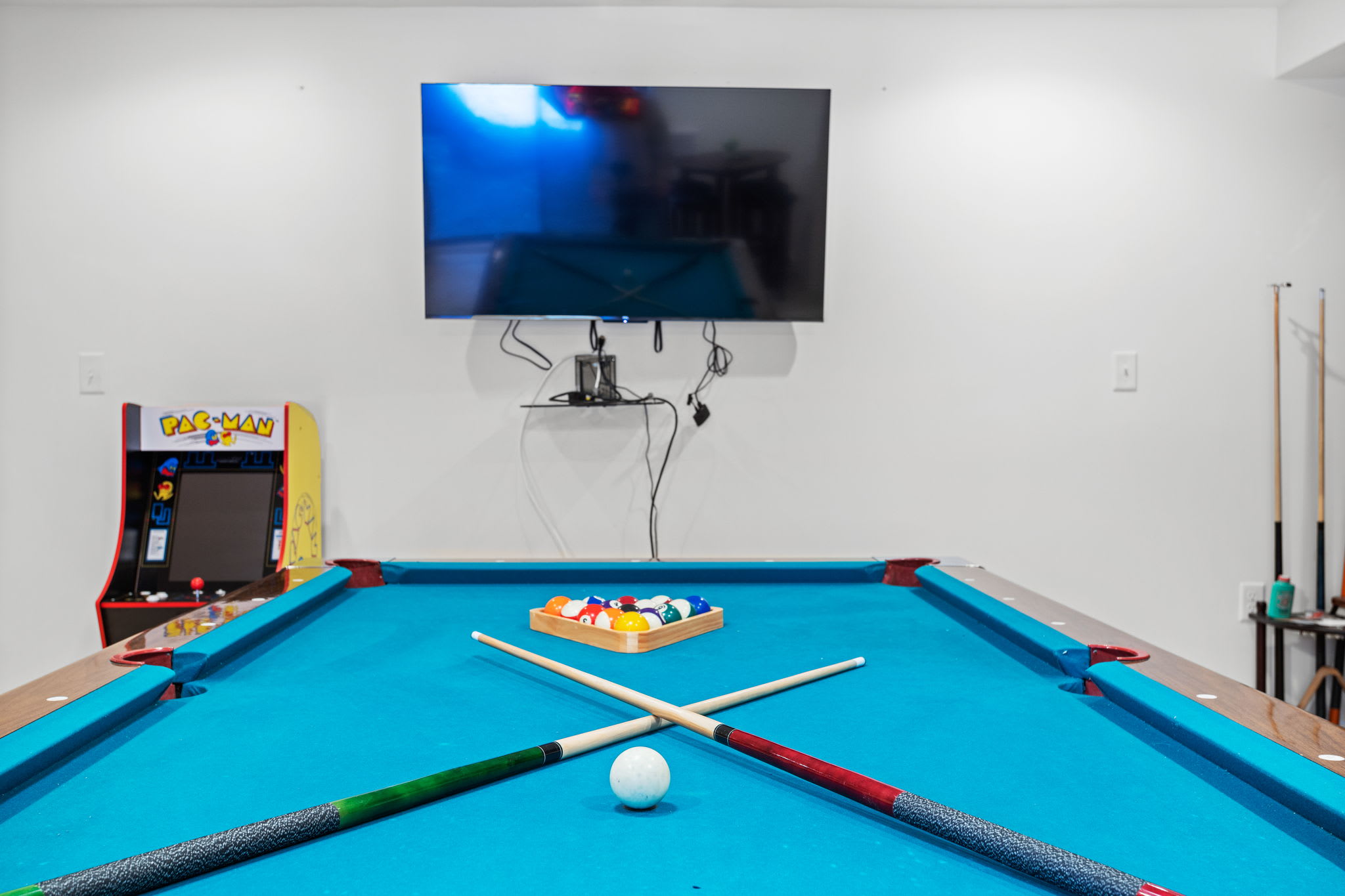 A game room built for fun, complete with a pool table, arcade game, and a mounted TV for the ultimate entertainment experience.