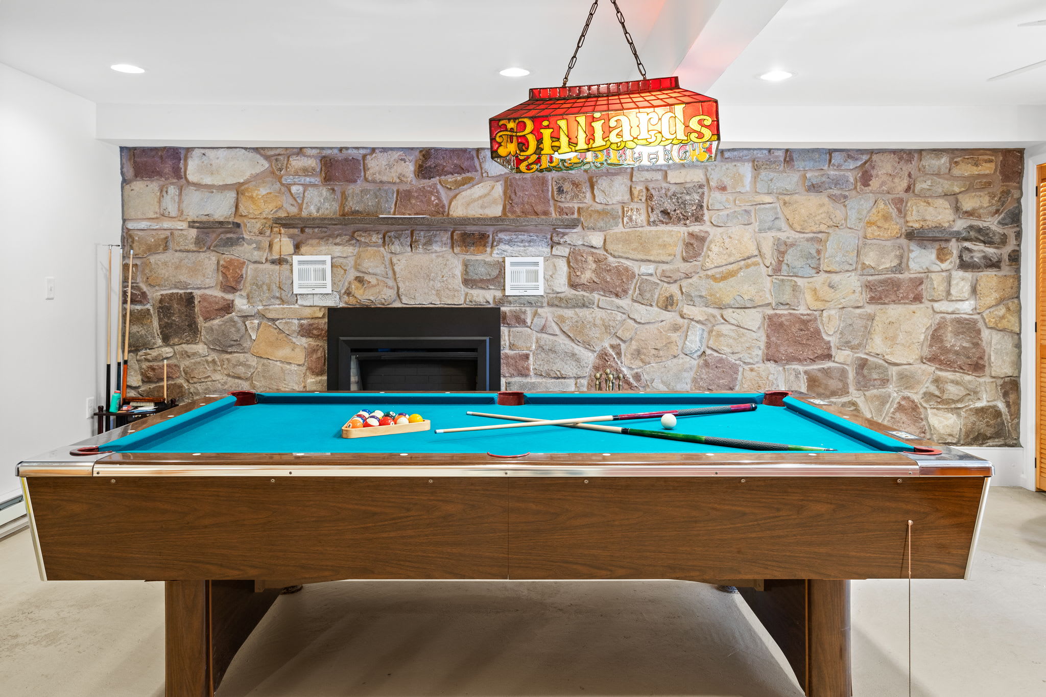 A vibrant pool table set against a stone-accented fireplace, creating the perfect mix of fun and relaxation.