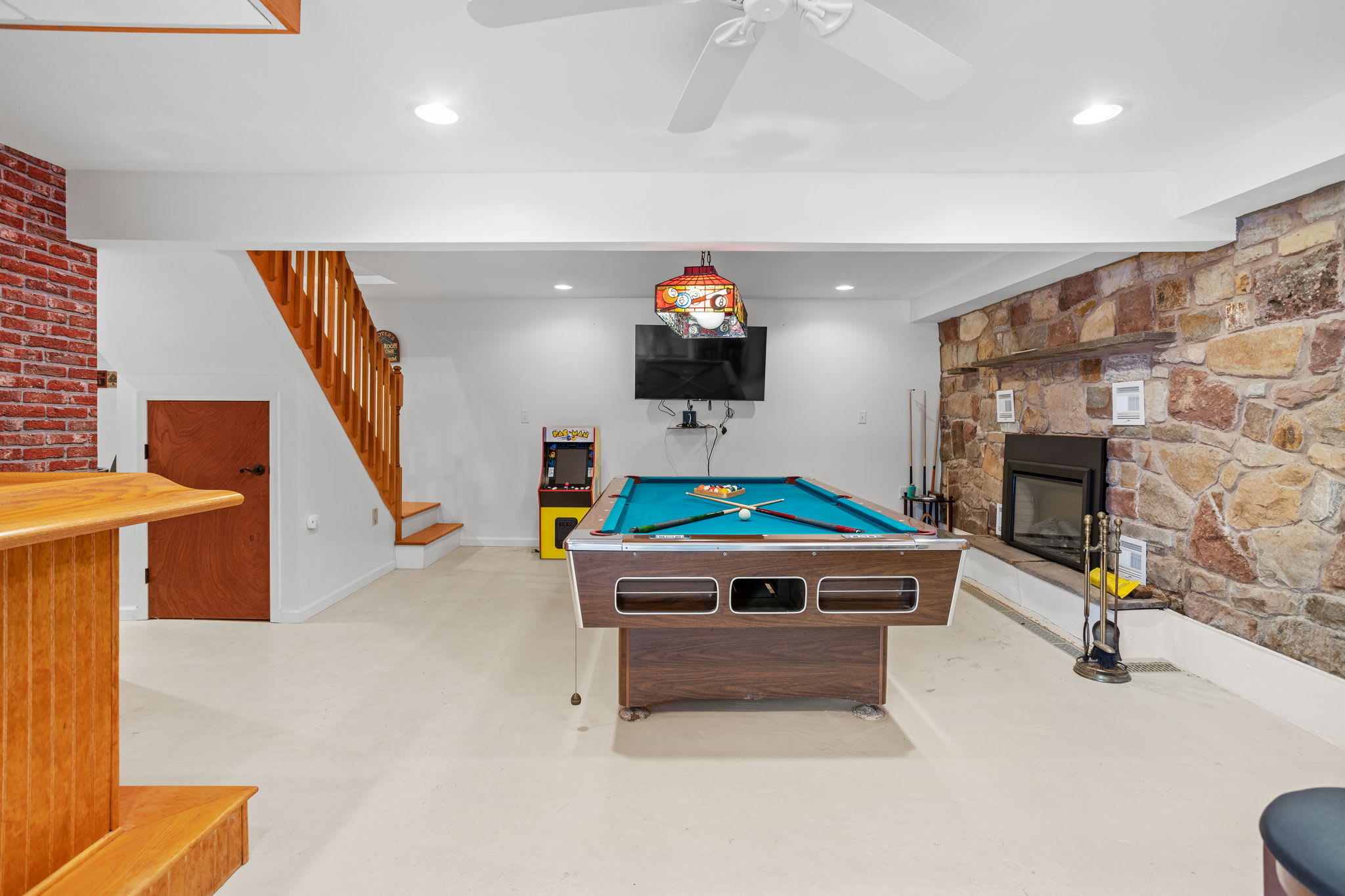 A spacious entertainment area featuring a classic pool table, arcade games, and a cozy atmosphere for endless fun.
