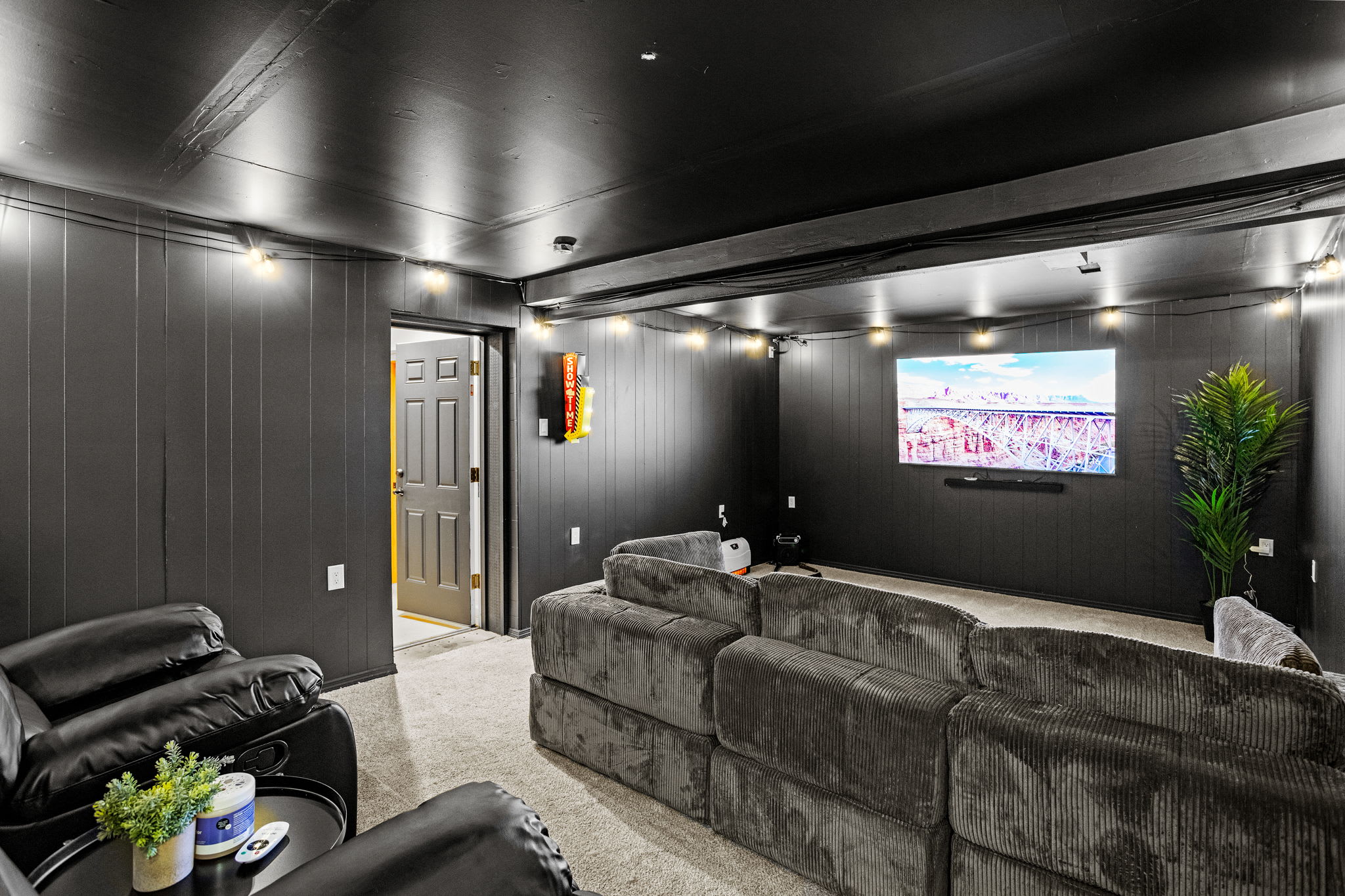 The dark-paneled walls and soft carpeting create a cozy atmosphere, while pops of greenery add a refreshing touch.