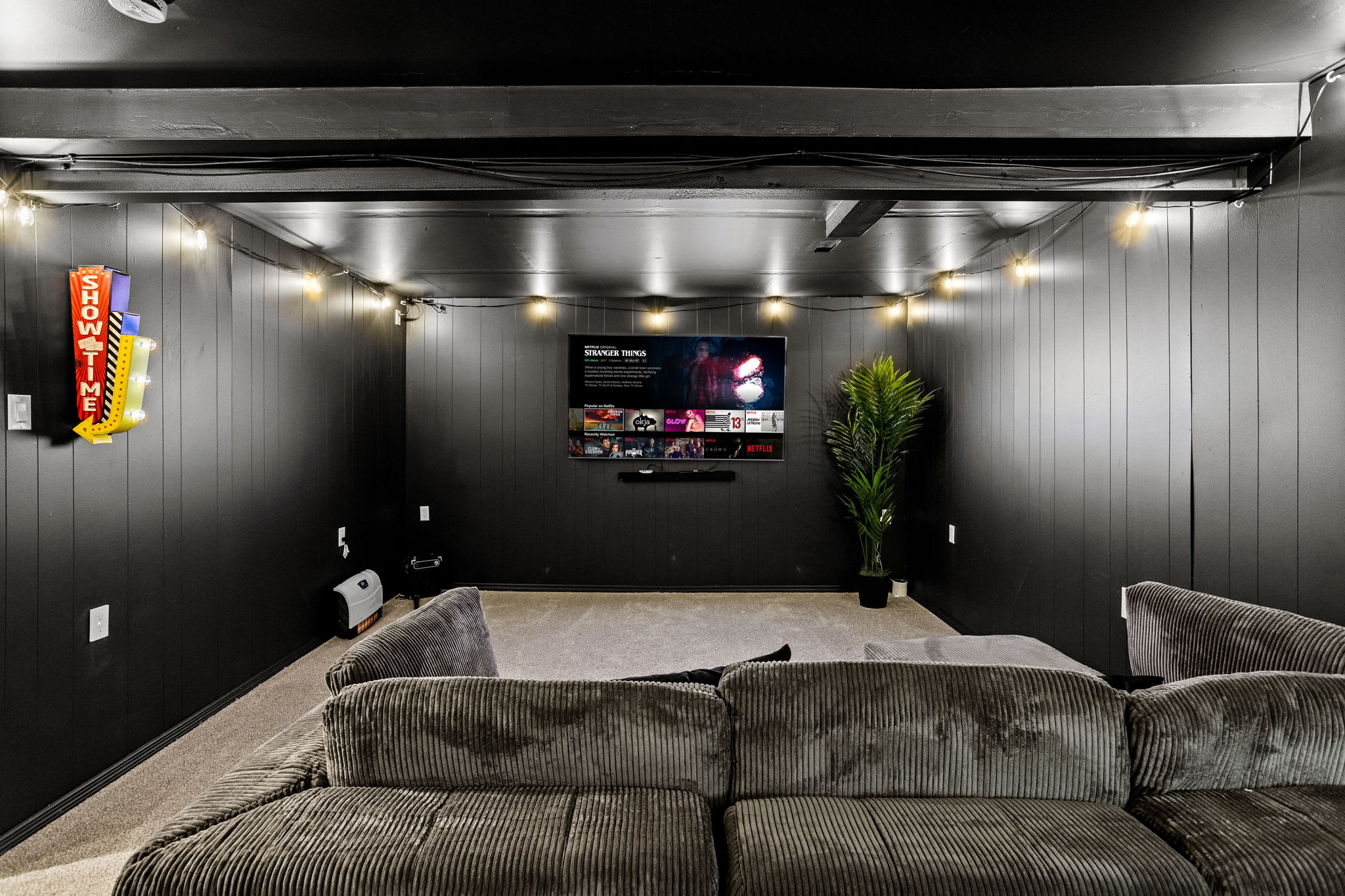 A sleek, modern home theater with plush seating, dimmable string lighting, and a large screen for an immersive cinematic experience.