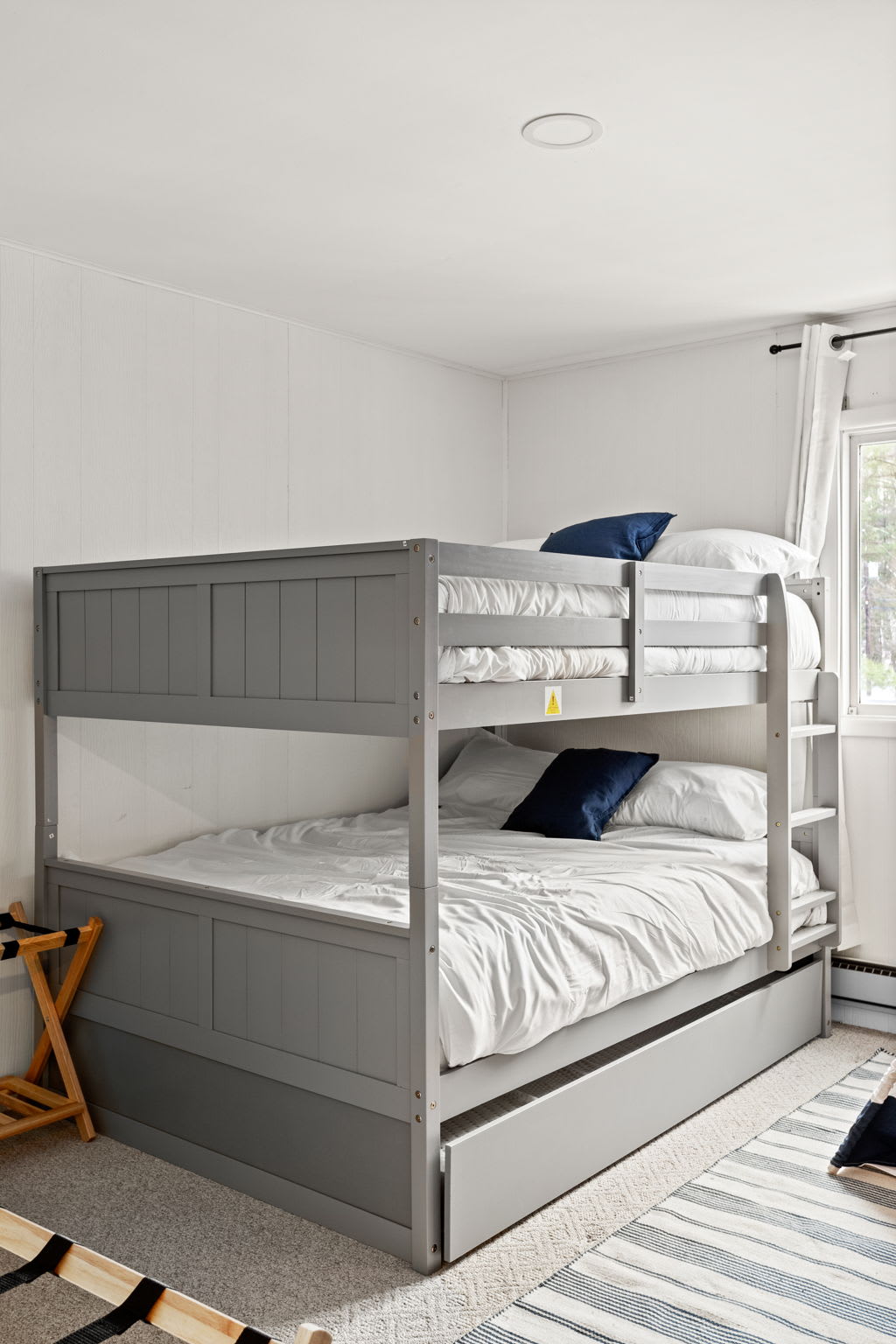A modern bunk bed setup that maximizes space and comfort. Plush bedding and soft lighting make this the perfect sleepover spot for kids or extra guests. (1 Bunk Bed with 1 single pull-out bed under)