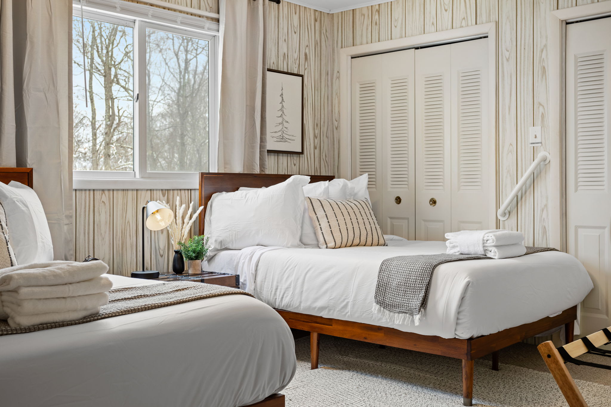 A large, airy bedroom with soft neutral tones, wood paneling, and a cozy ambiance for a restful stay. (2 Queen Size Bed)
