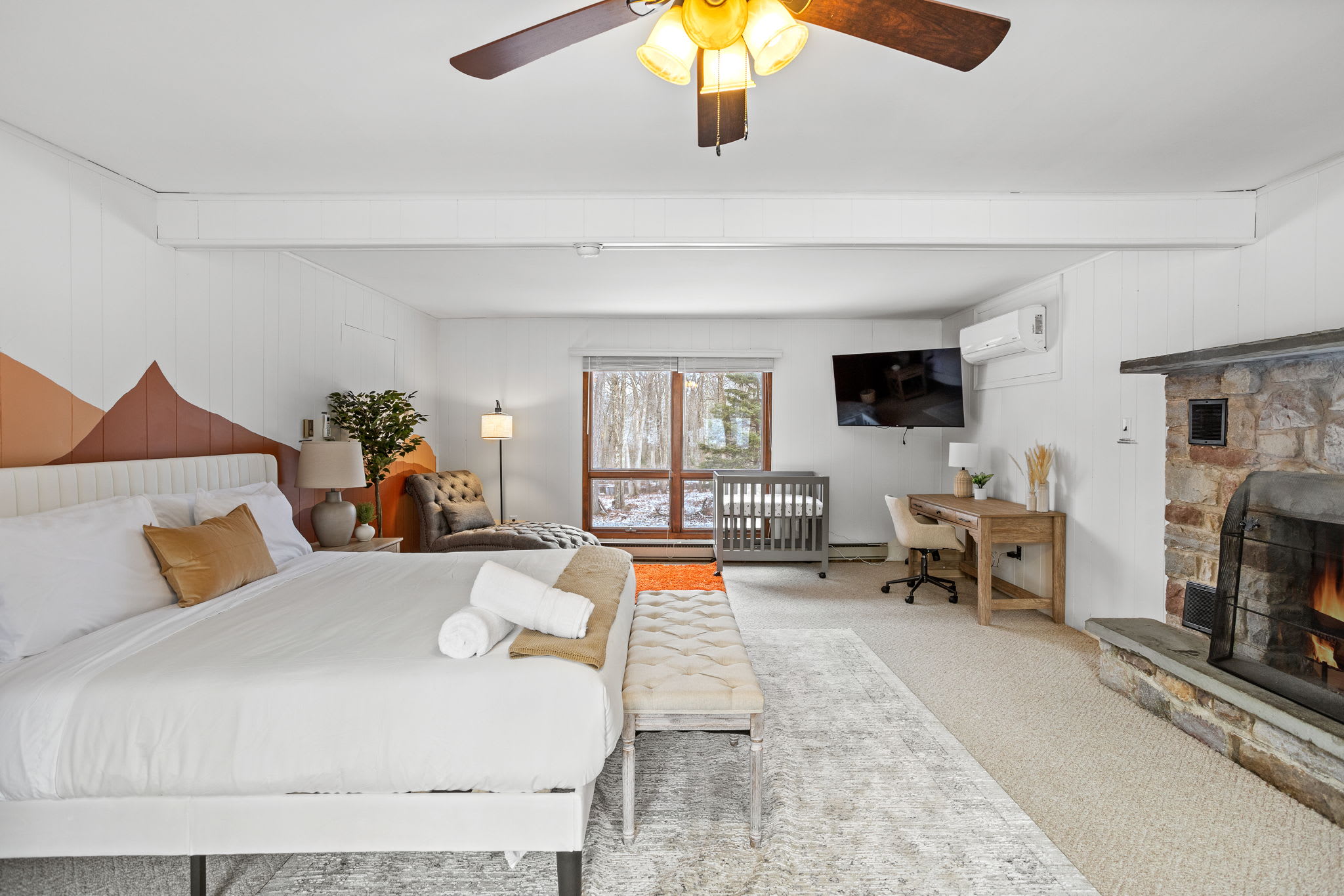 A spacious master suite with a warm fireplace, plush bedding, and soft natural light, ideal for a restful and luxurious stay.