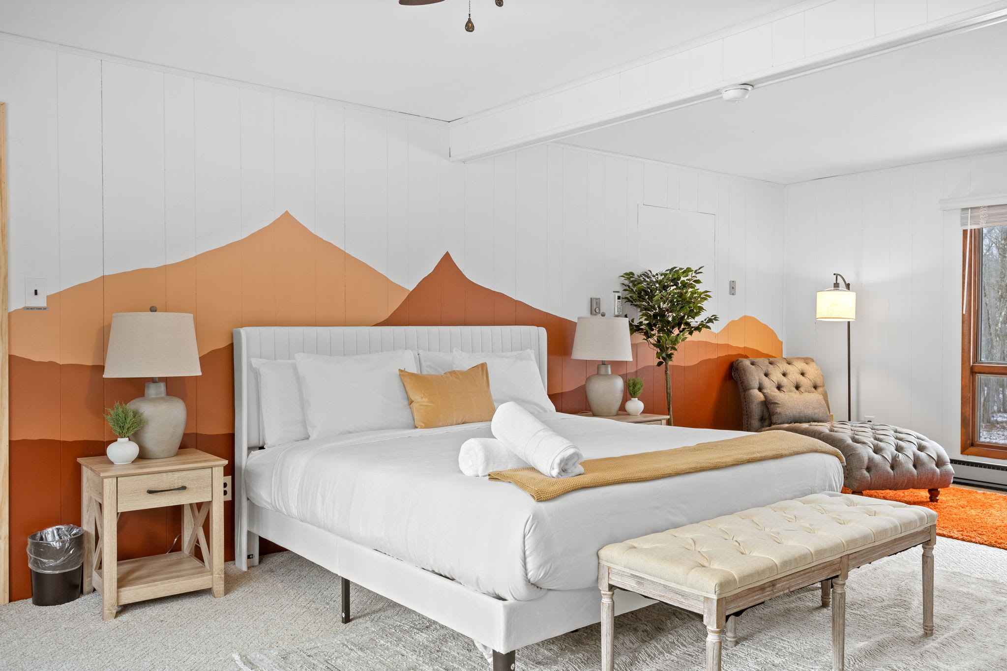 A serene and inviting space featuring a king-size bed with a modern mountain-inspired accent wall. Soft, neutral tones and warm lighting create the perfect retreat after a long day.