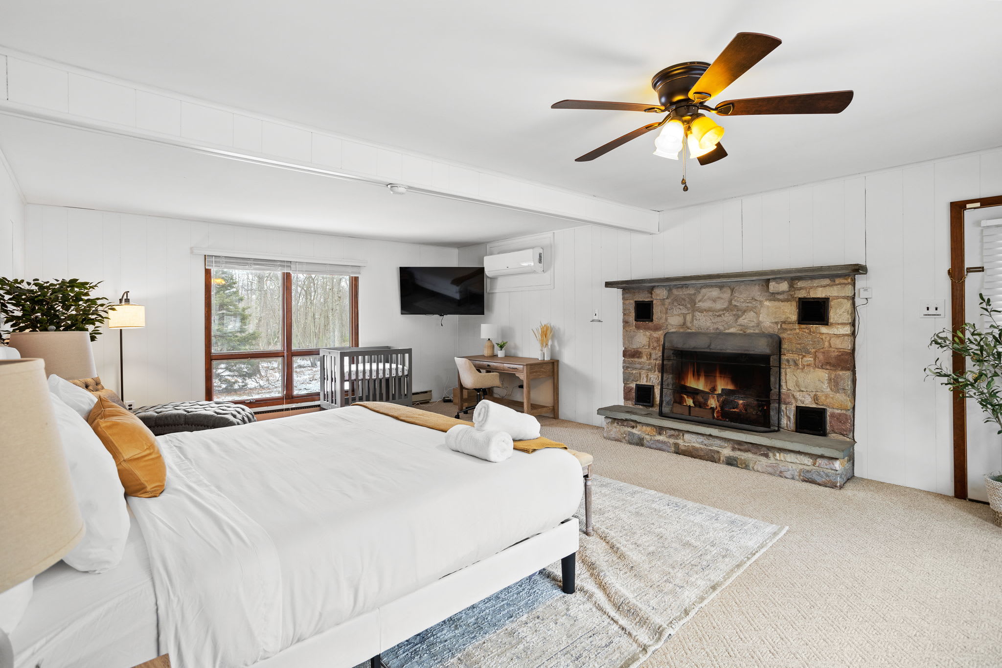 Wake up to stunning views and cozy up by the stone fireplace in this beautifully designed bedroom. Large windows bring in natural light, making the space feel bright and airy.