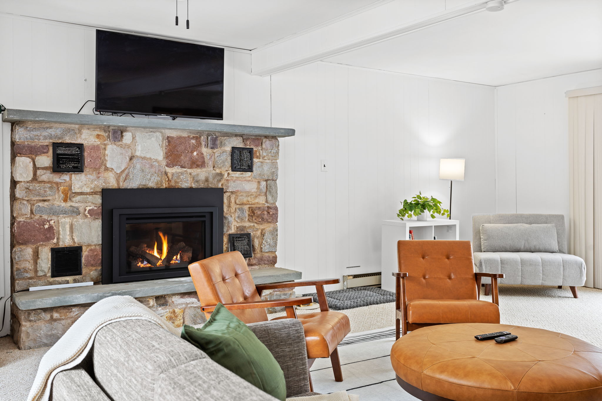 Gather around the charming stone fireplace for a cozy night in, complete with a mounted TV and plush seating.
