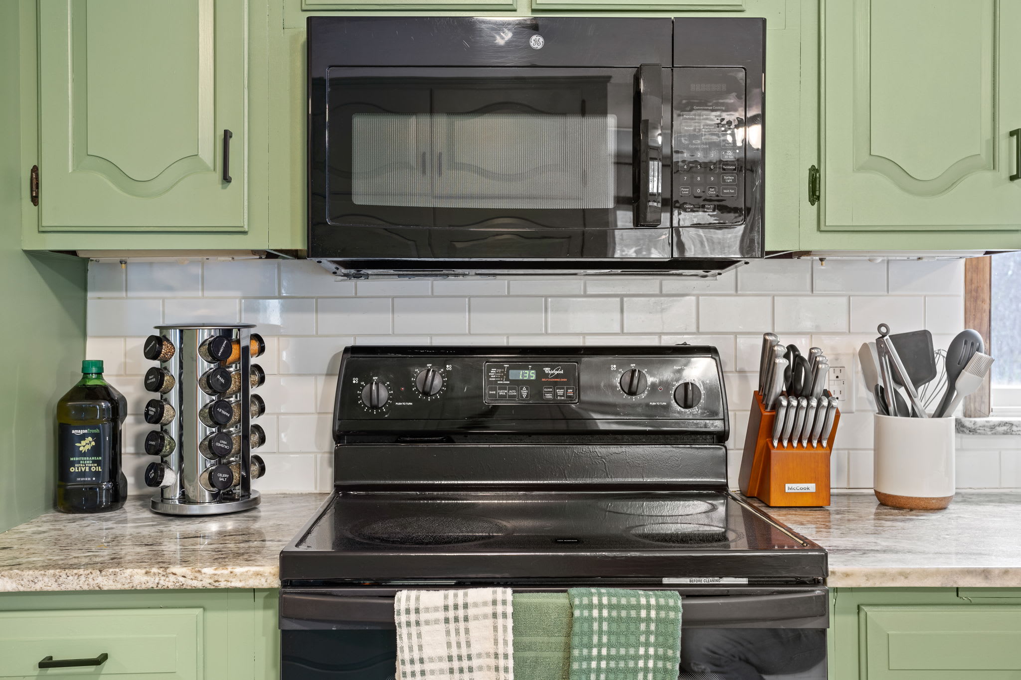 A closer look at the modern cooking area, featuring a smooth black range, a stylish backsplash, and all the essentials.