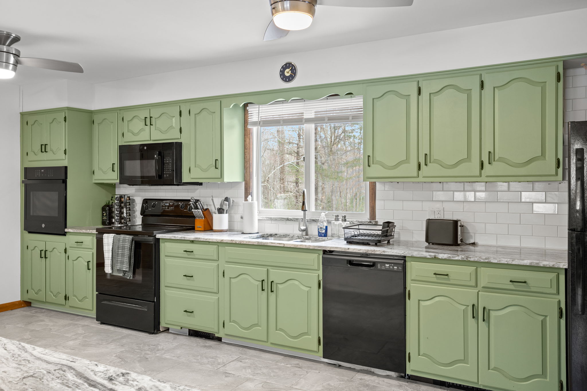 This fully equipped kitchen offers generous counter space, striking green cabinets, and modern appliances.