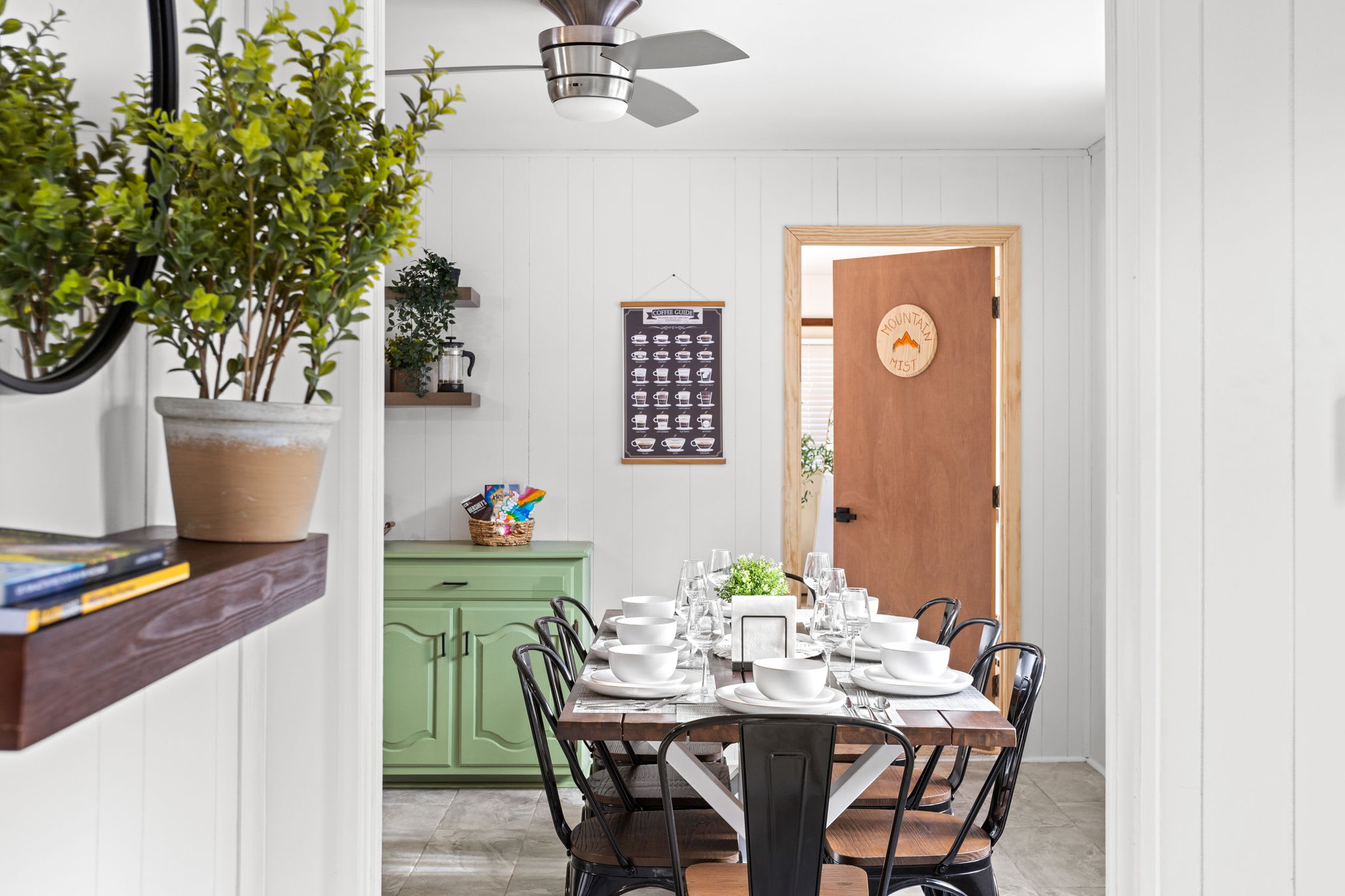 A beautifully set dining table ready for shared meals, with warm wood tones and greenery adding a cozy touch.