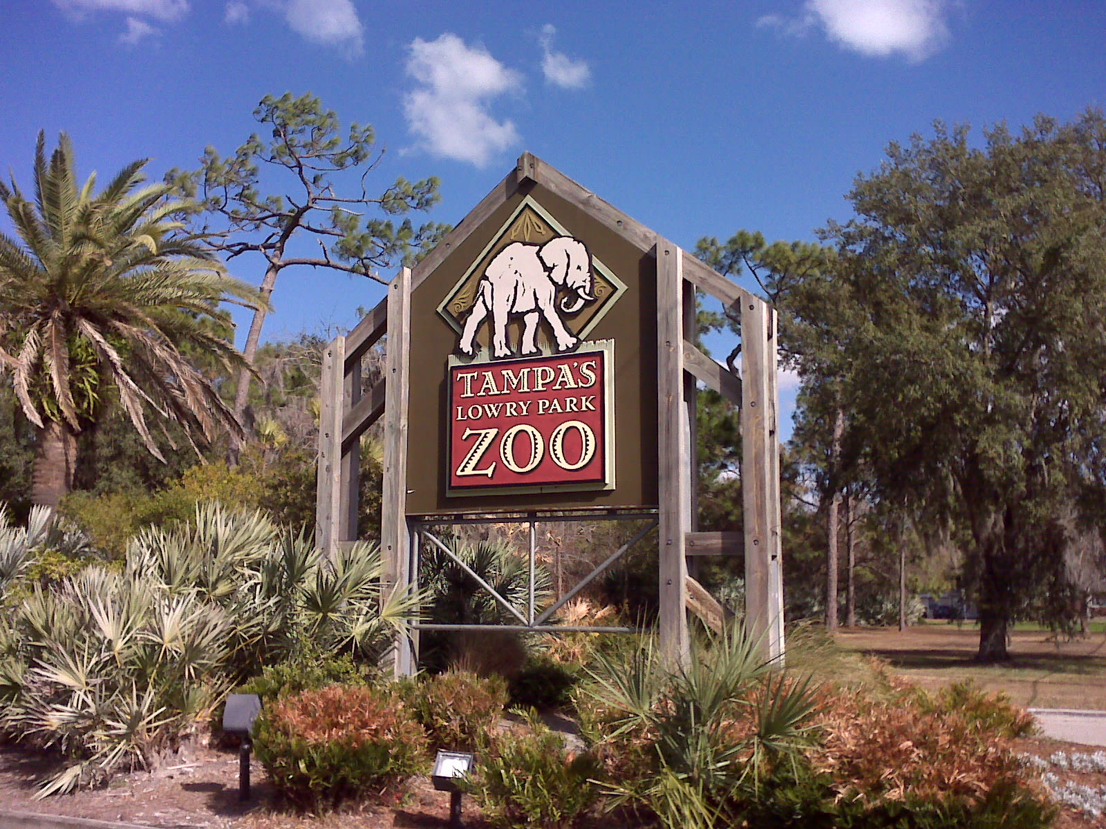 Welcoming entrance sign framed by palm trees for a sunny arrival vibe.