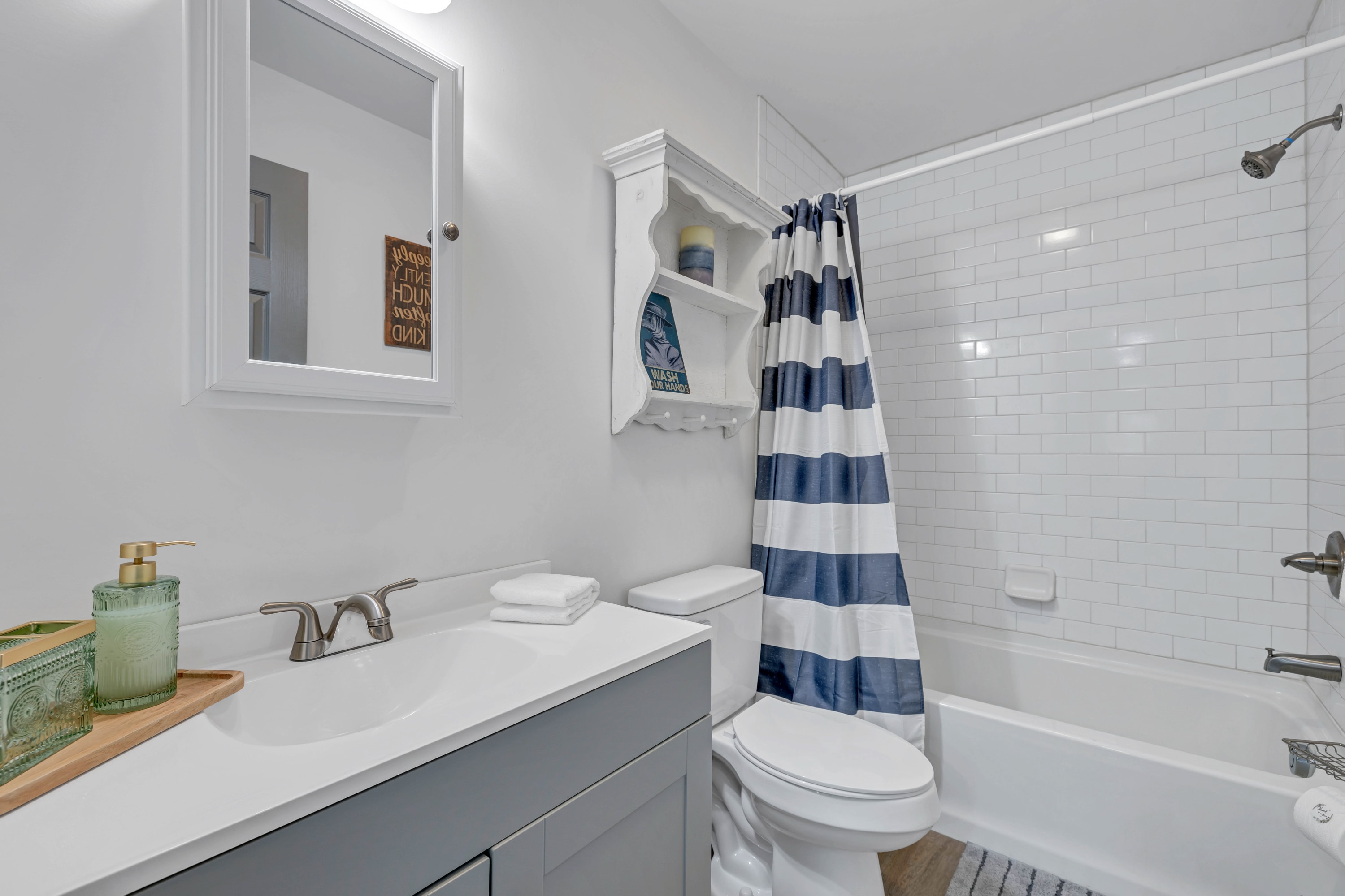 Modern bathroom with tub and shower combo, mirror, and all the essentials provided for your convenience and comfort.