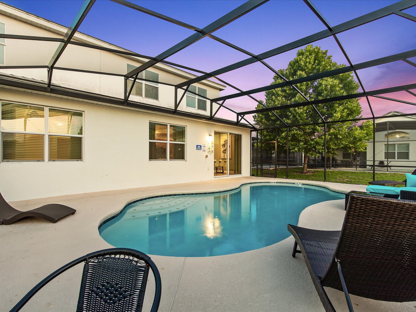 Screened-in pool glowing at dusk, perfect for evening swims.