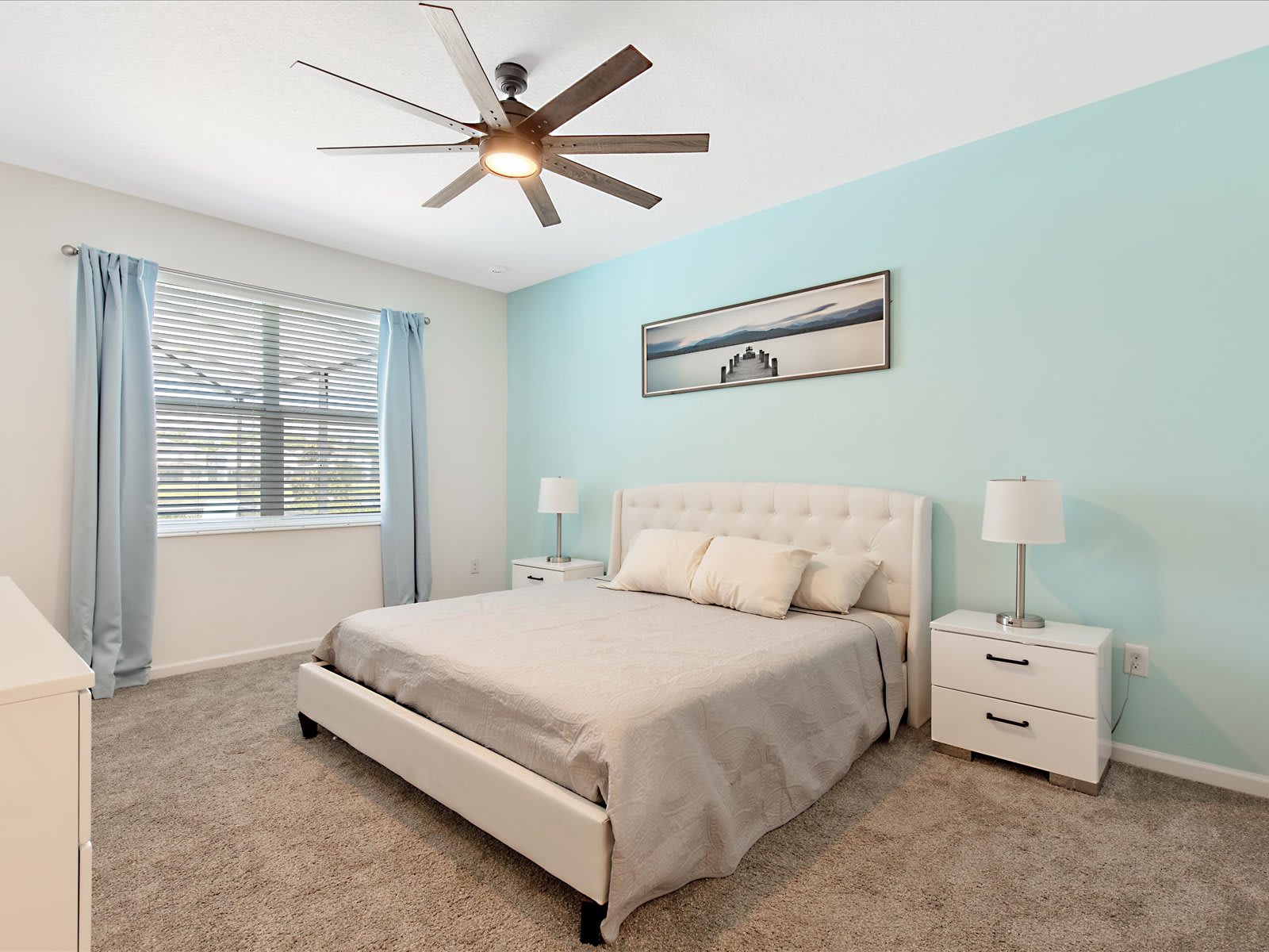 Serene bedroom w/ soft tones, cozy bed, & ceiling fan for restful nights.