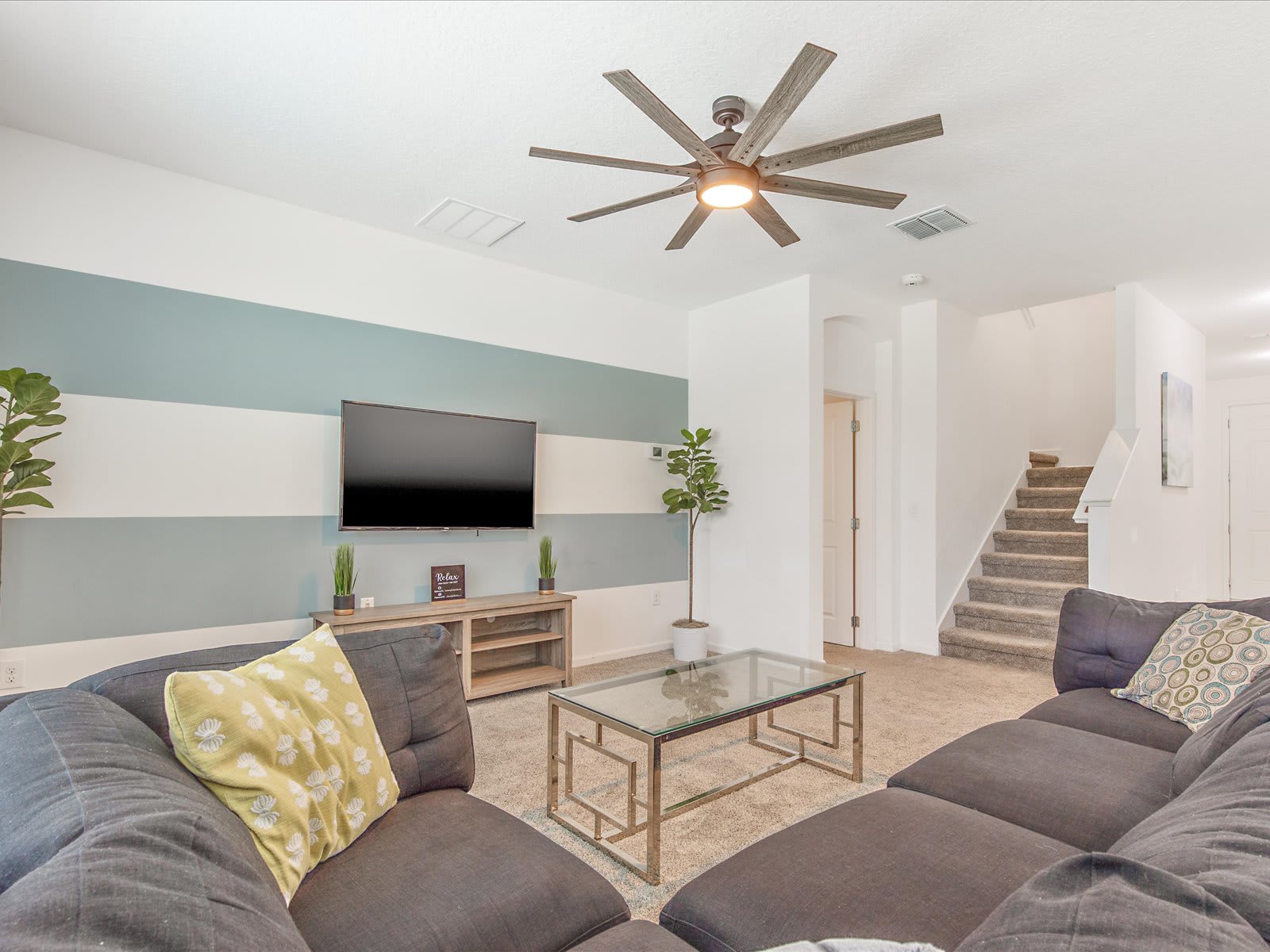 Bright living room w/ plush seating, ceiling fan, & TV for easy lounging.