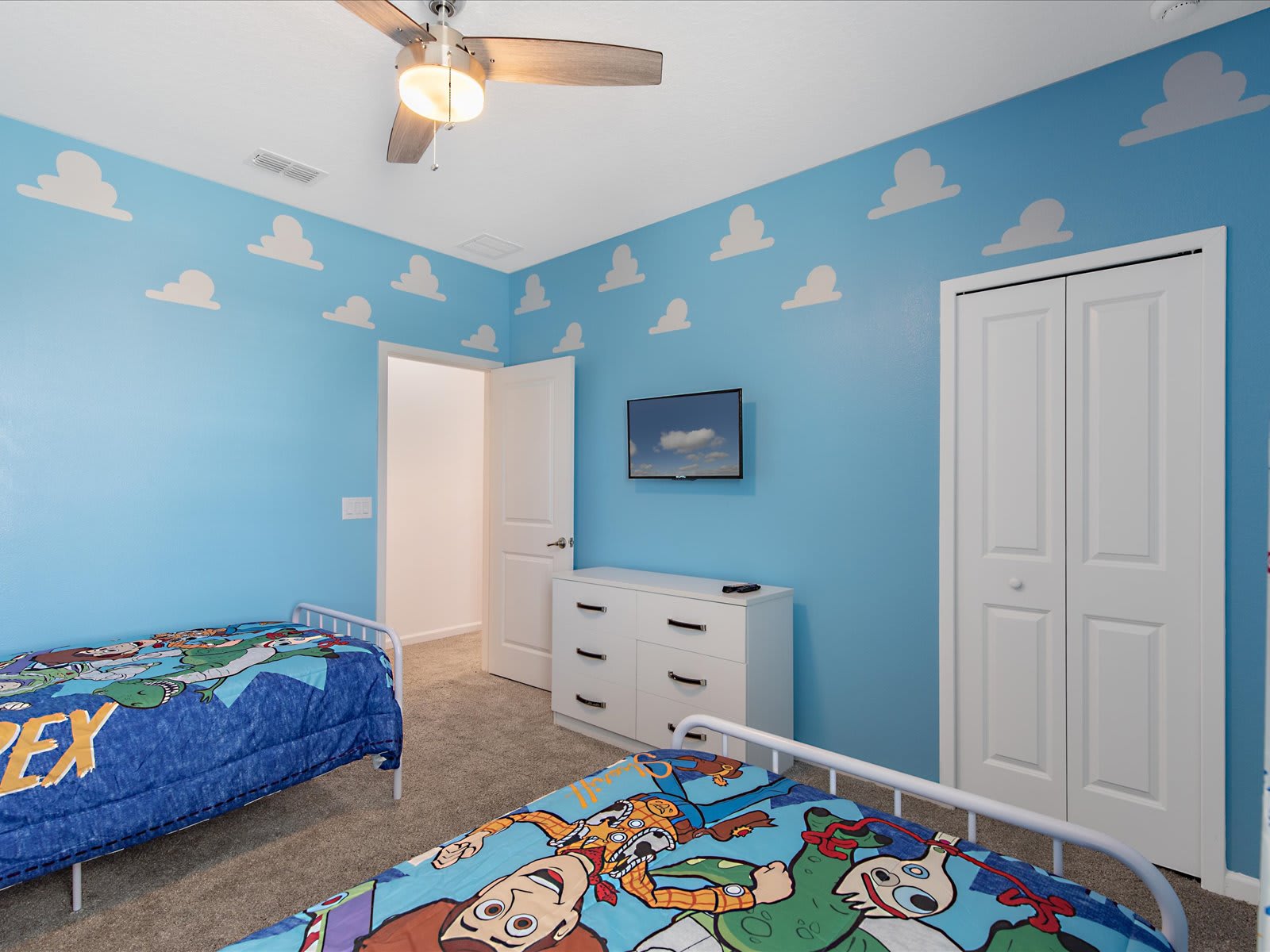 Playful kids’ room w/ colorful bedding & sky-themed walls.