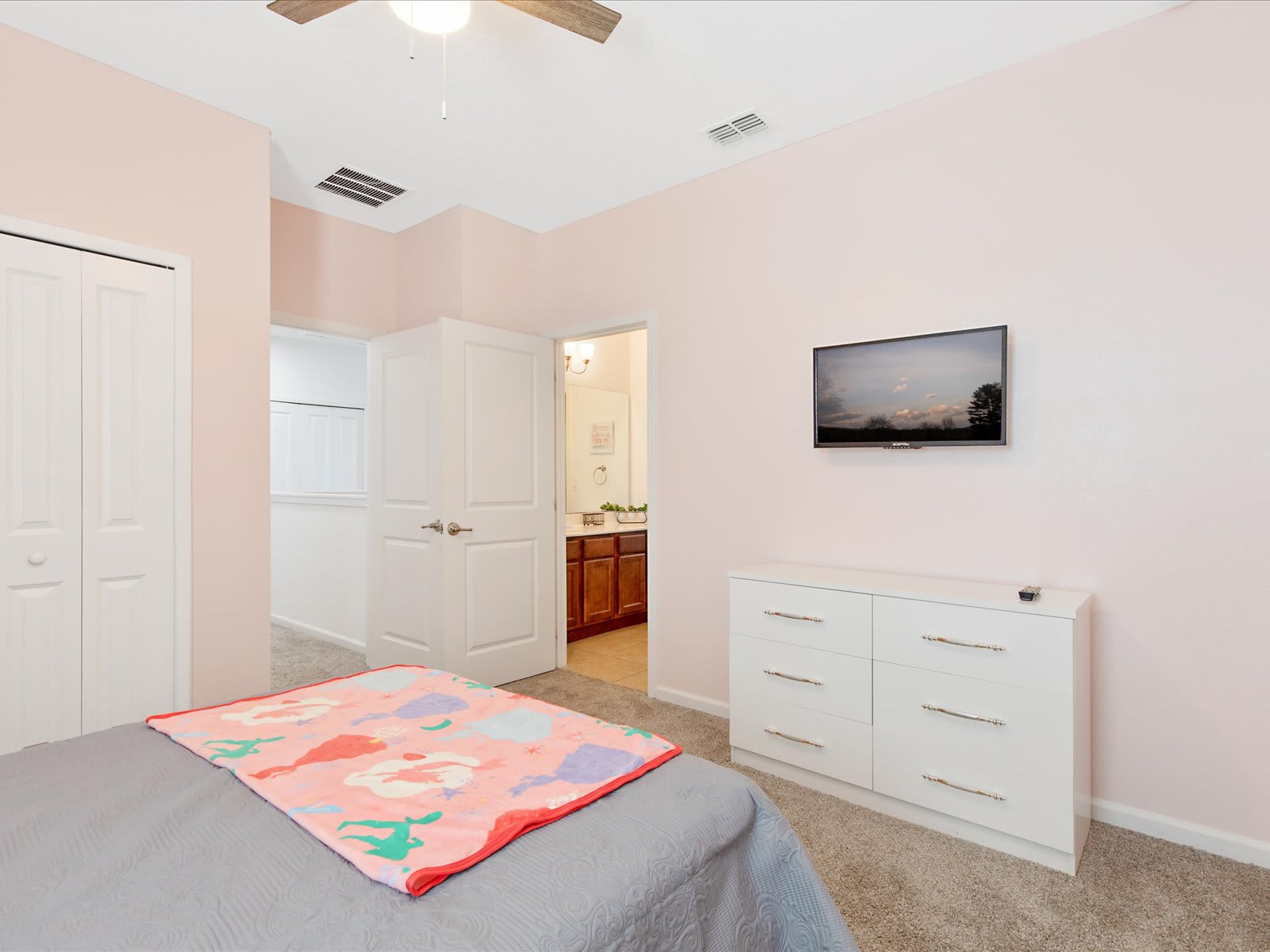 Airy bedroom w/ dresser, TV, & simple, comfortable design.