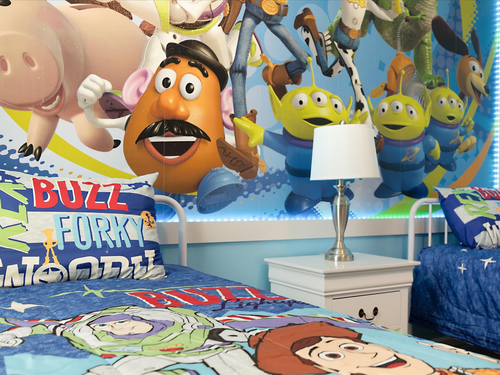 Colorful Toy Story–themed room bursting w/ character art & cozy beds.