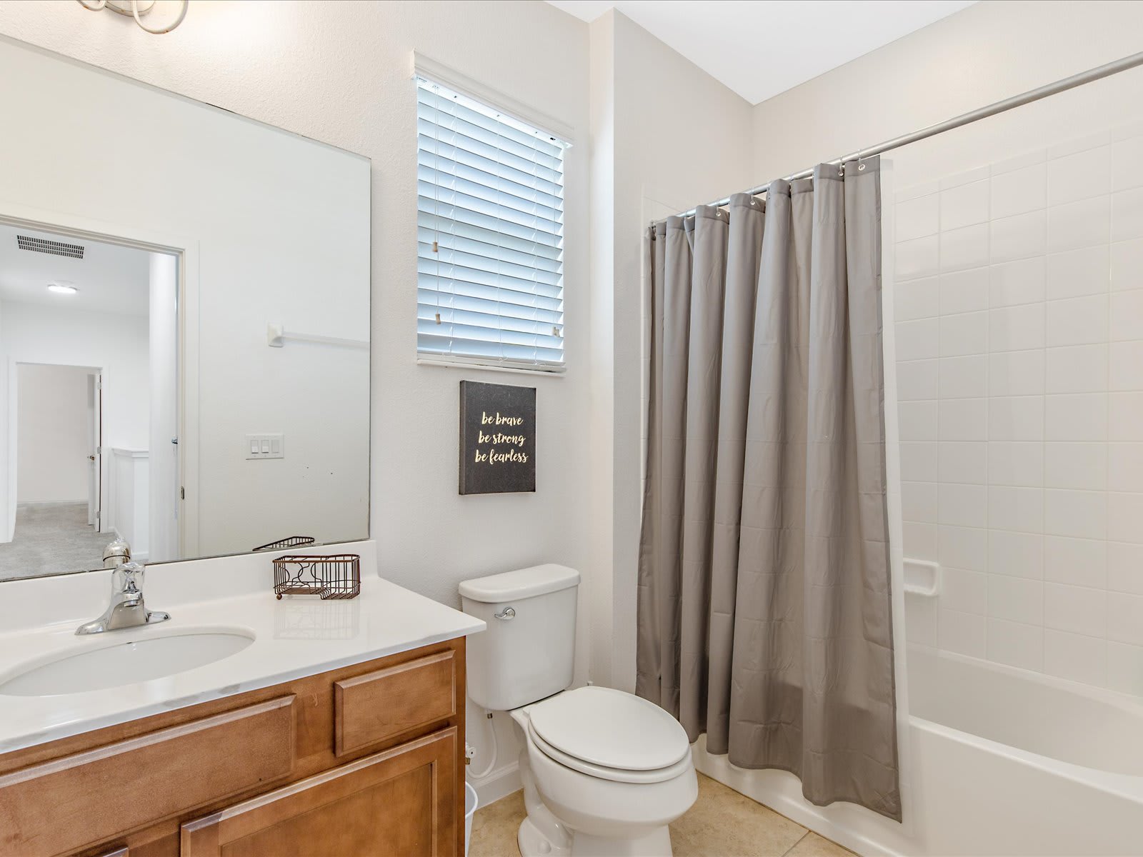 Fresh bathroom w/ sink, toilet, & tub/shower combo w/ soft curtains.