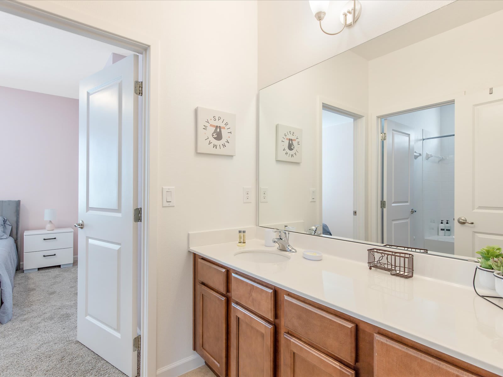 Spacious bathroom w/ long vanity, ample counter space, & large mirror.