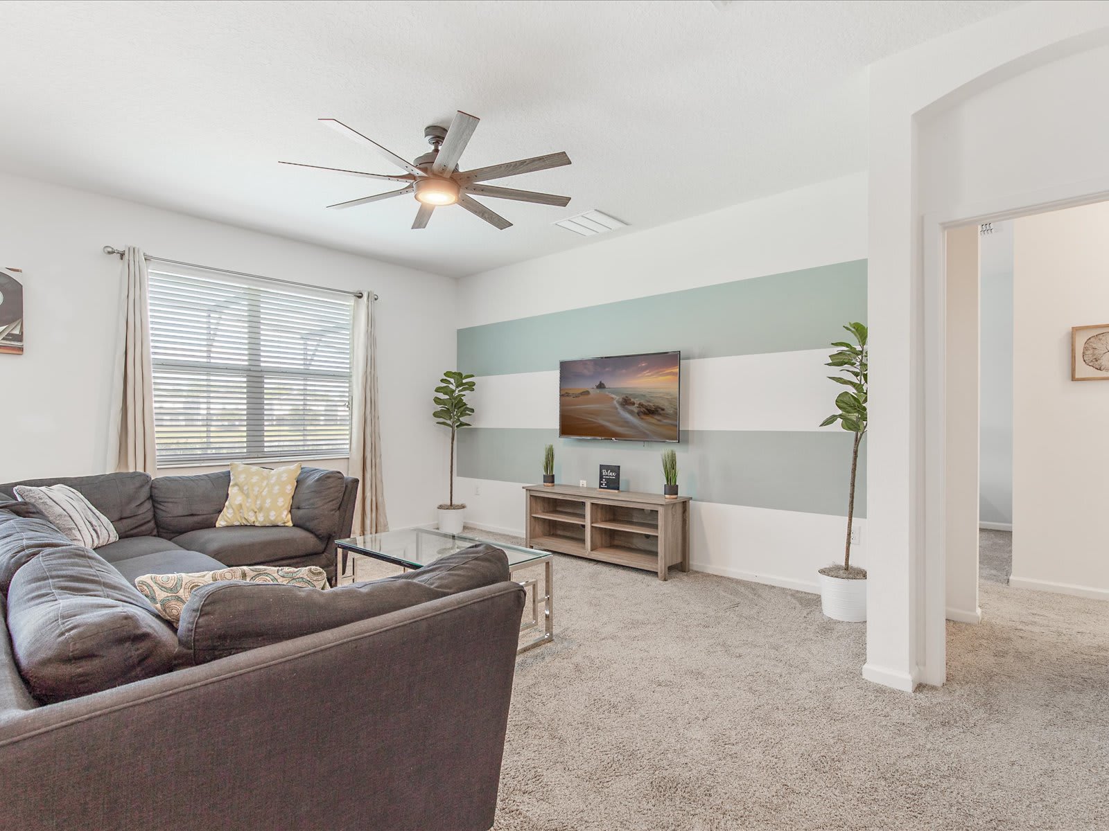 Comfortable living room w/ plush seating, ceiling fan, & TV.