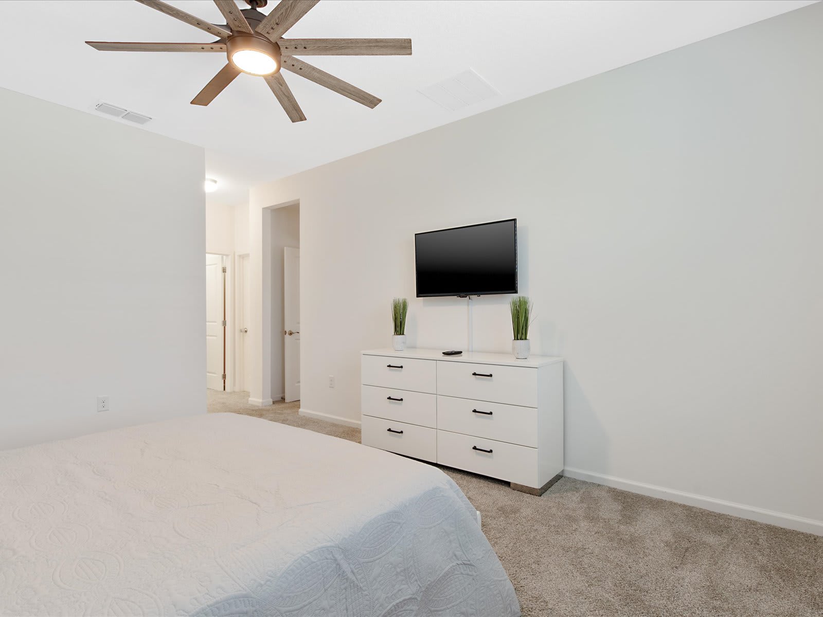 Serene bedroom w/ cozy bed, ceiling fan, & TV for unwinding.
