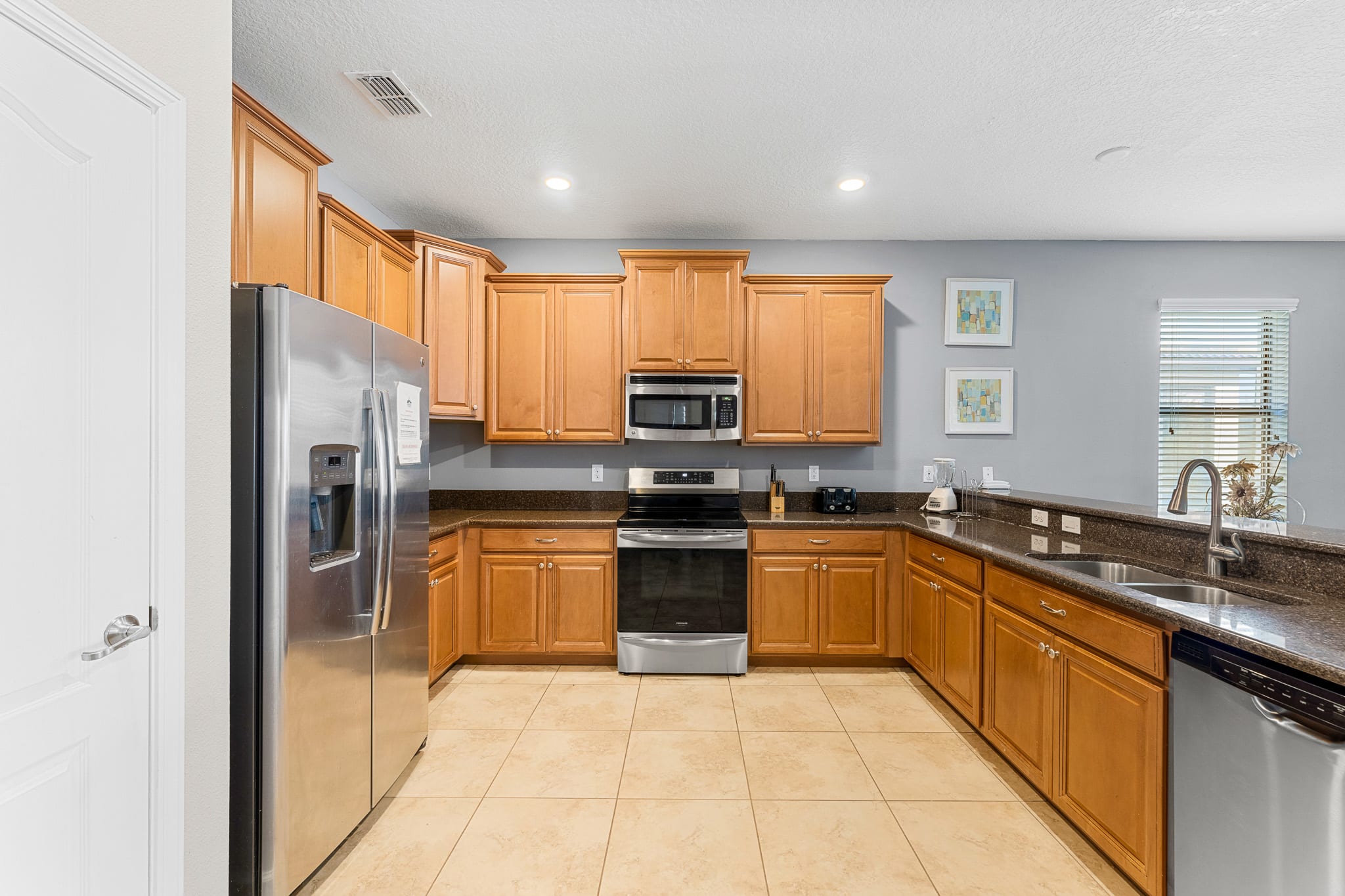 Open kitchen w/ large island, modern appliances, and bar seating.