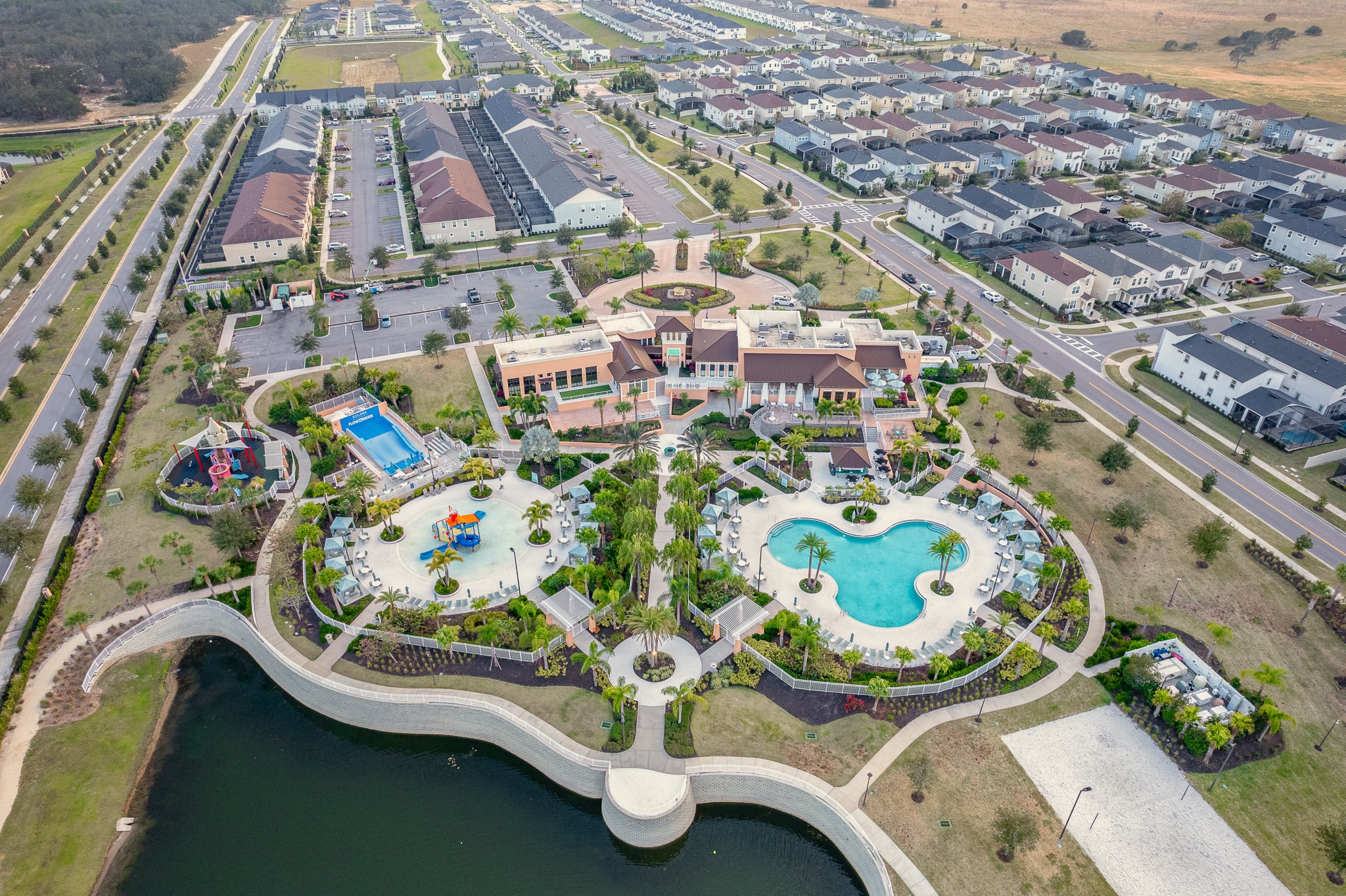 Aerial view of a resort-style community featuring a large pool, water playground, and surrounding residential homes.