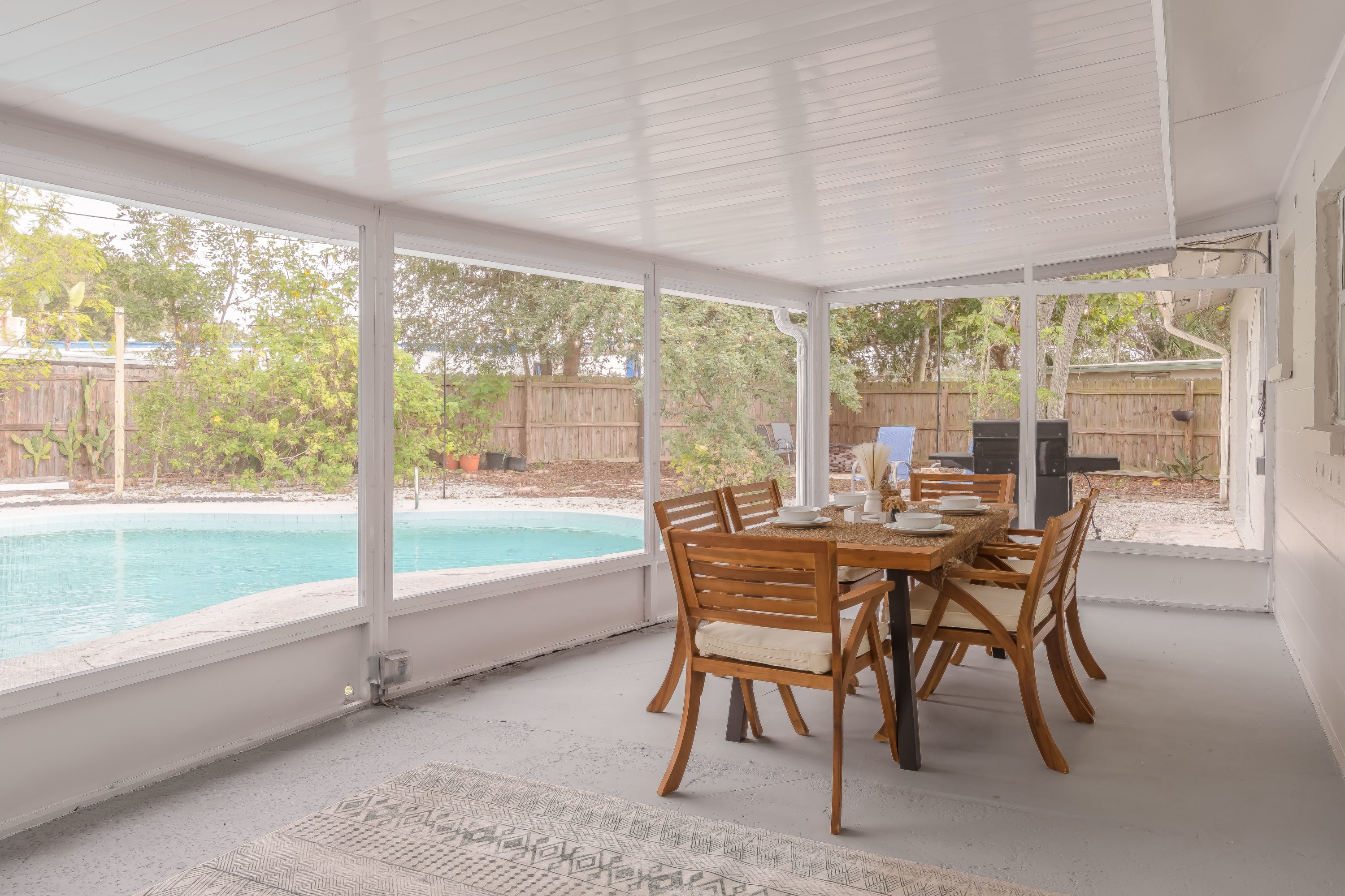 Screened patio dining area surrounded by greenery, perfect for alfresco meals.