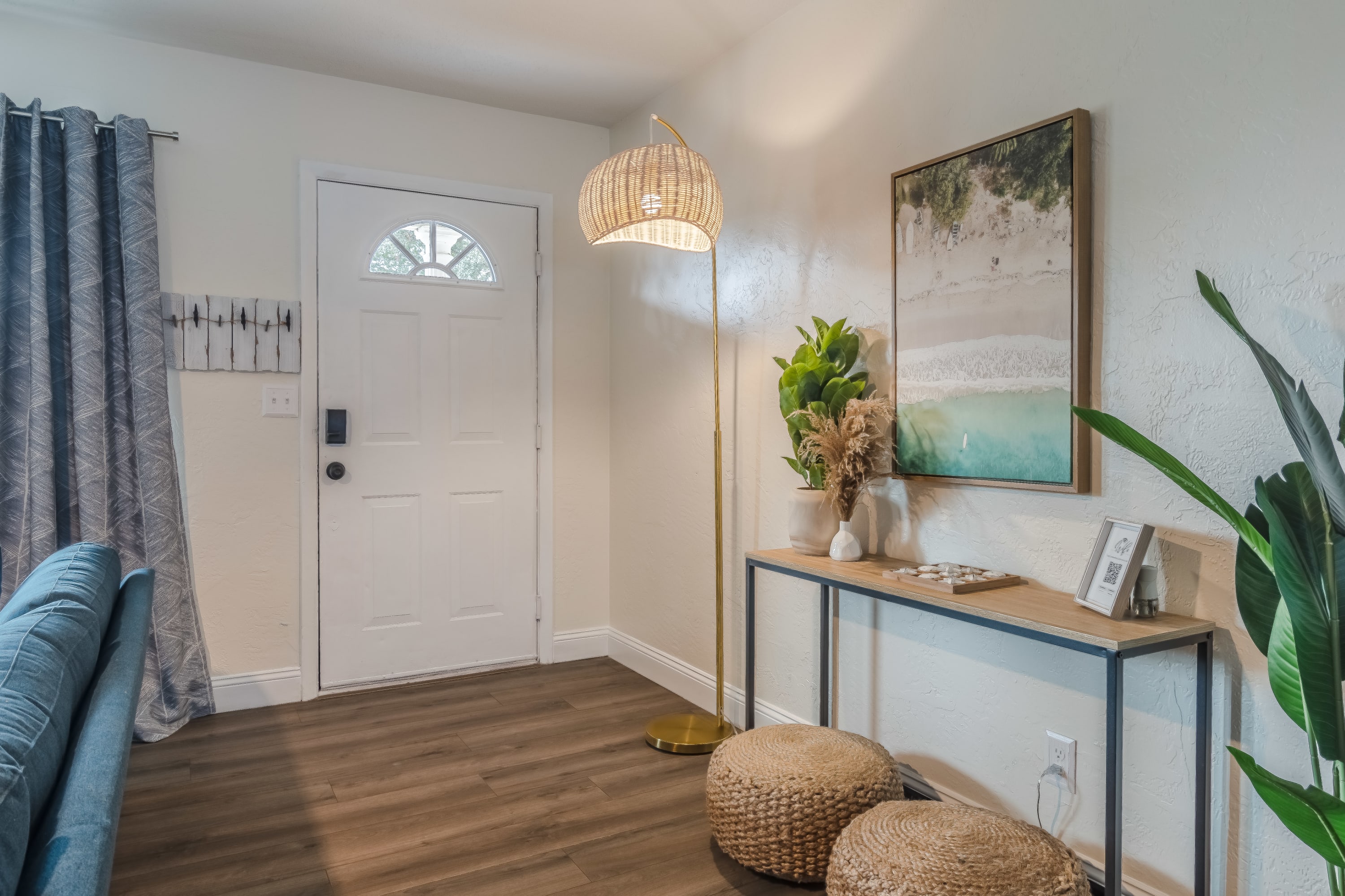 Welcoming entryway w/ console table, woven stools, and warm lighting that sets a relaxed tone on arrival.