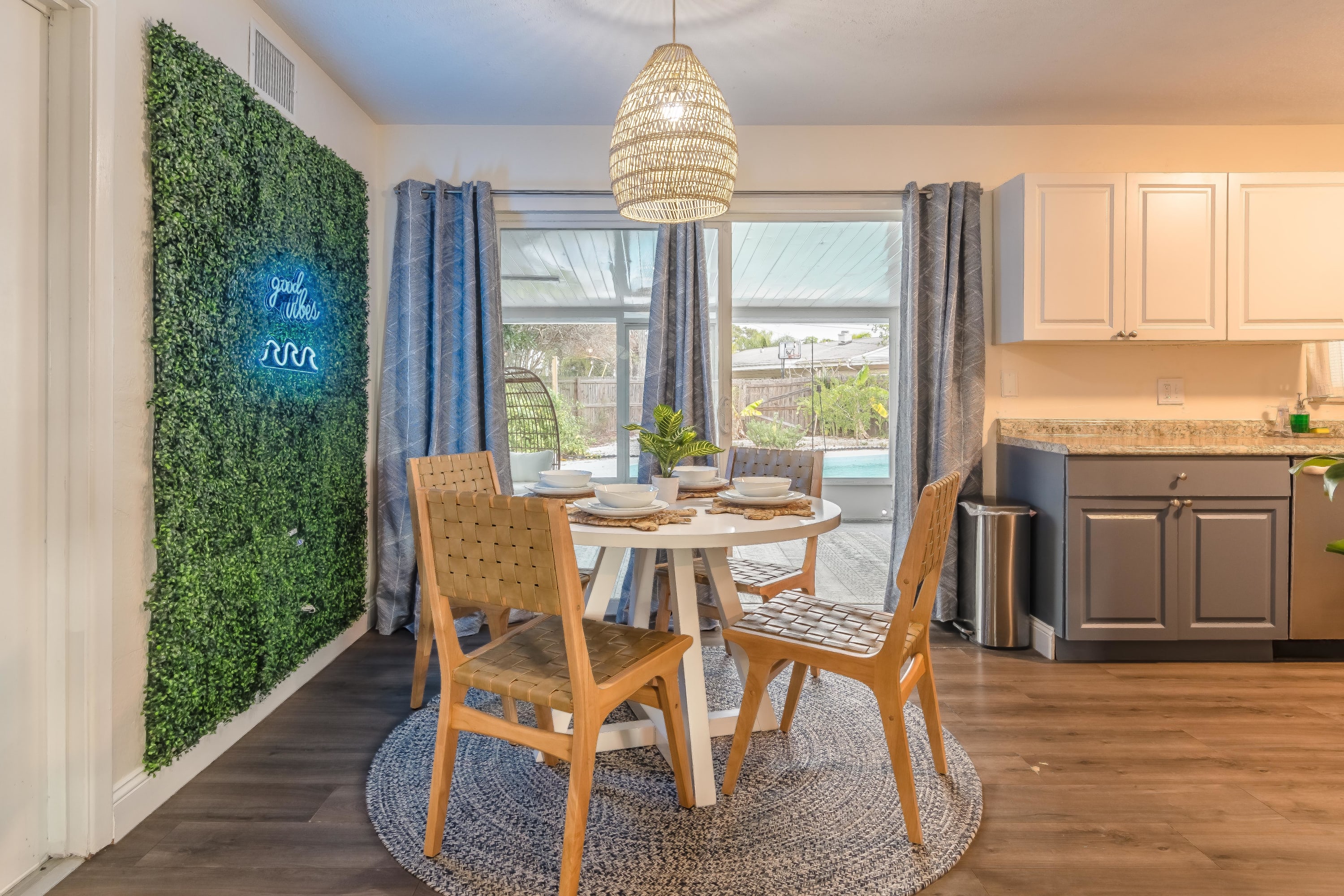 Bright dining area w/ round table and greenery just outside the windows.