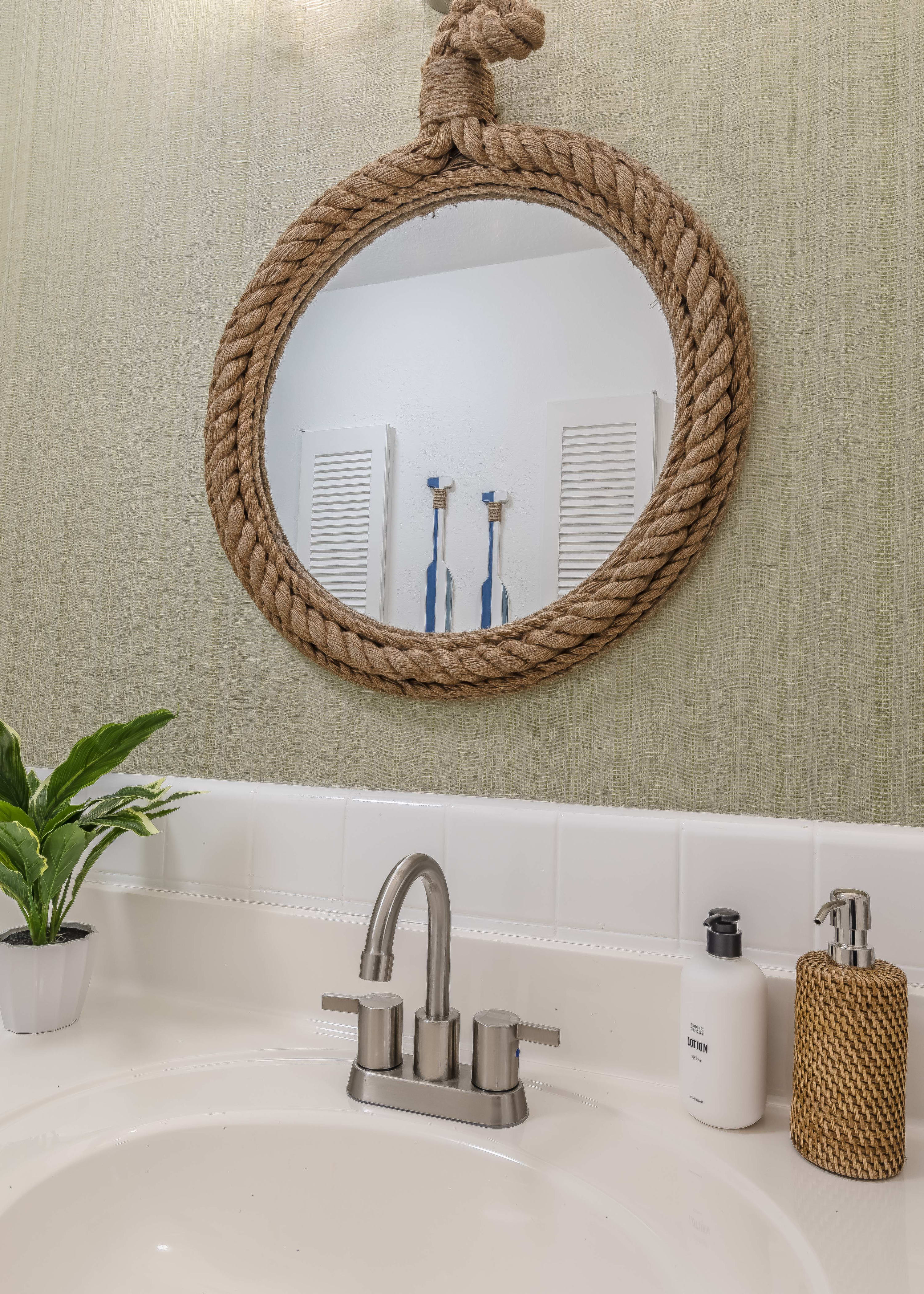 Bathroom vanity w/ round mirror and simple, calming decor.
