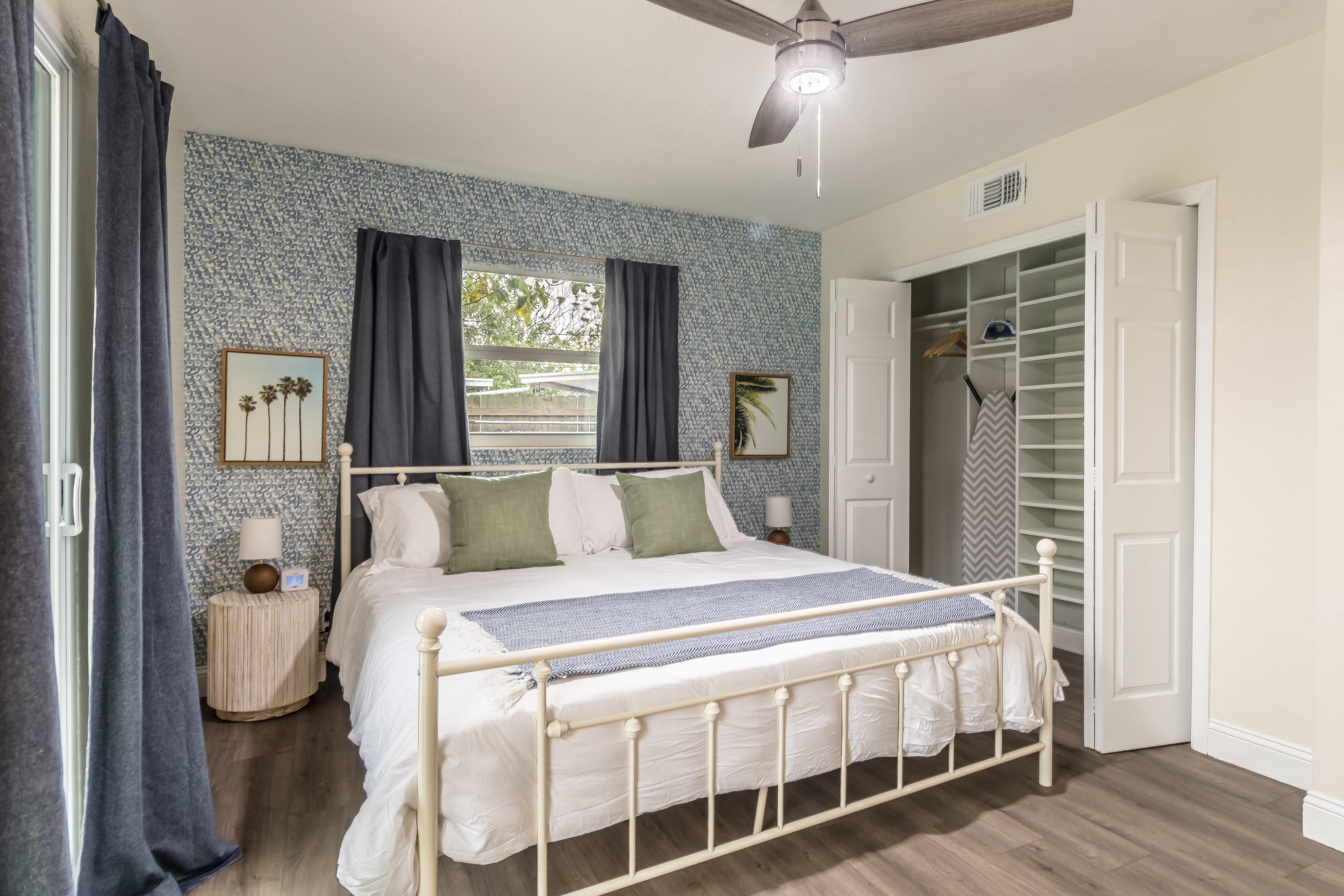 Spacious bedroom w/ large bed and natural light from wide windows.