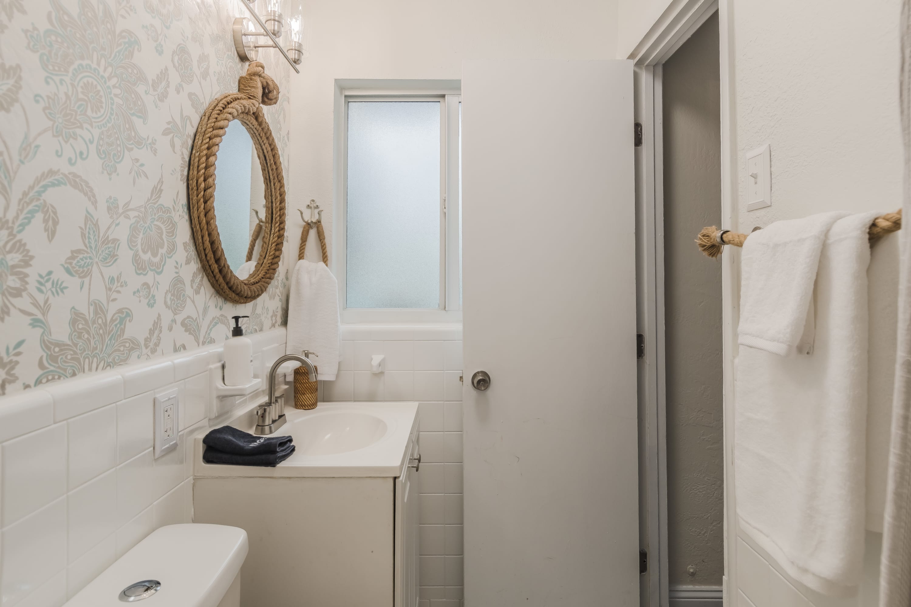 Bathroom vanity area w/ clean lines and bright, airy lighting.