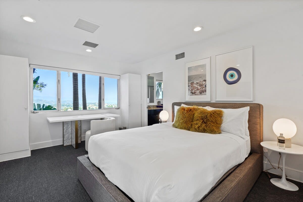 Modern bedroom with desk space and a window showcasing breathtaking views, offering a serene and inspiring environment.