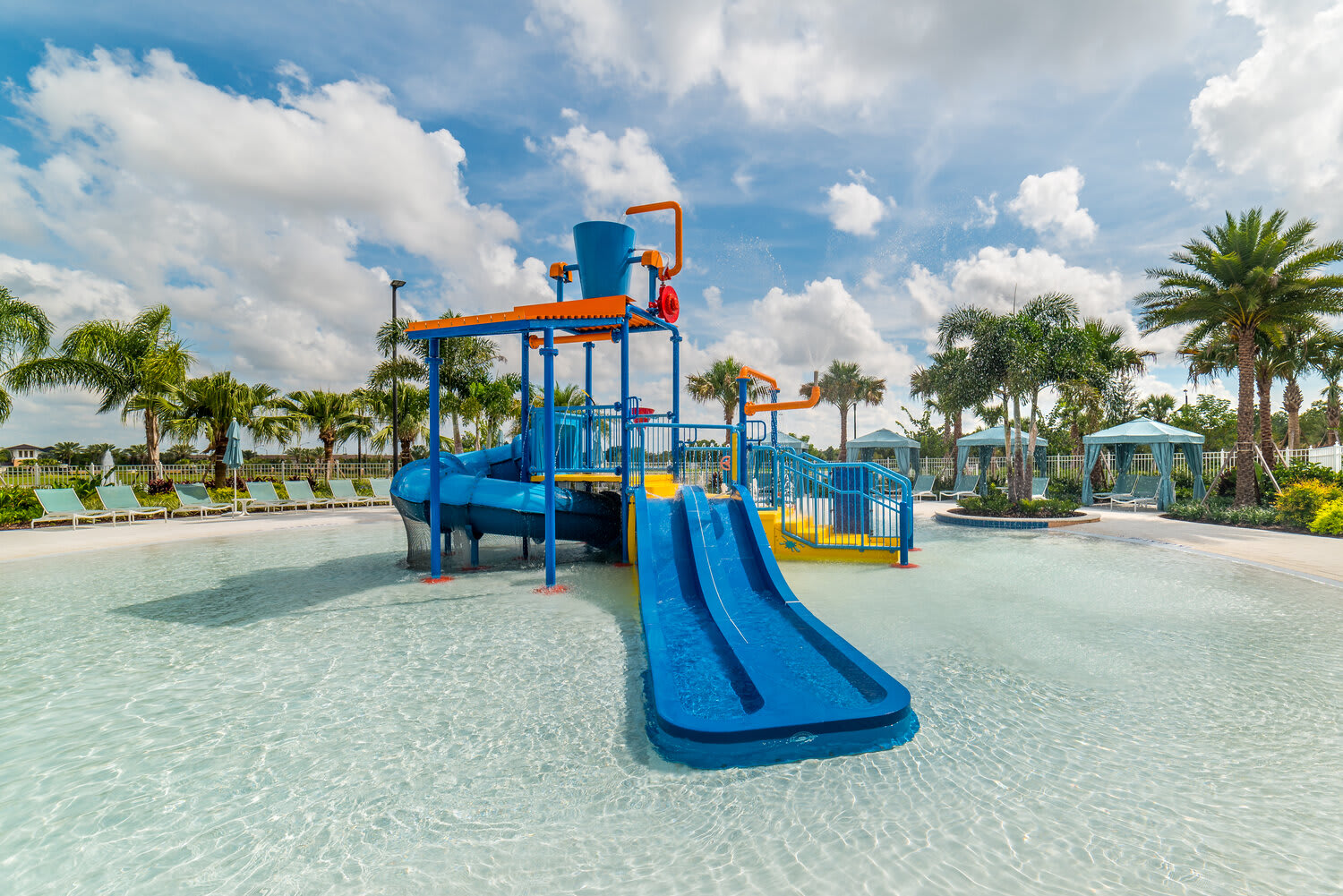 Family-friendly water play area with slides and splash features in a tropical setting.
