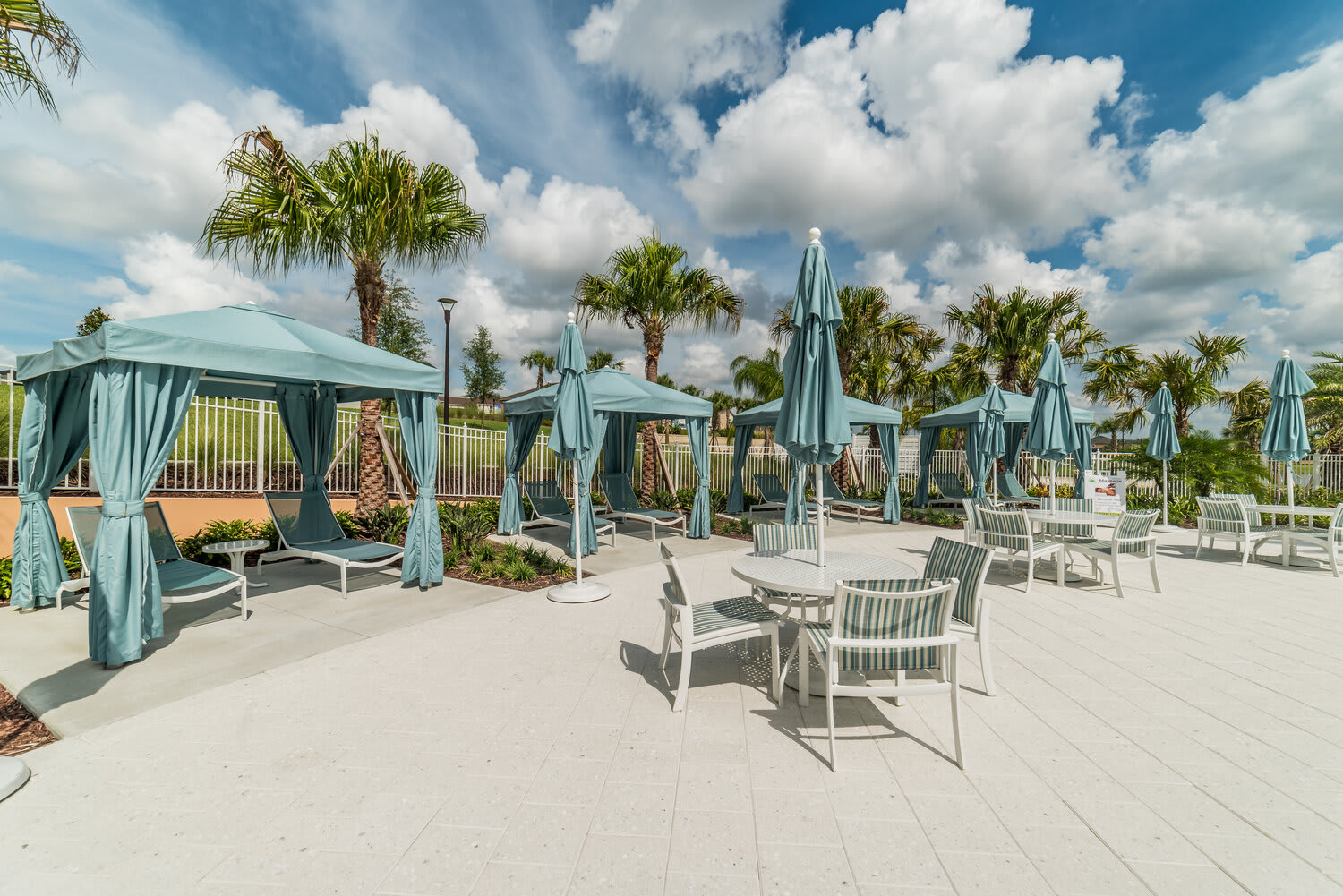 Outdoor lounge area with shaded cabanas and seating under blue umbrellas