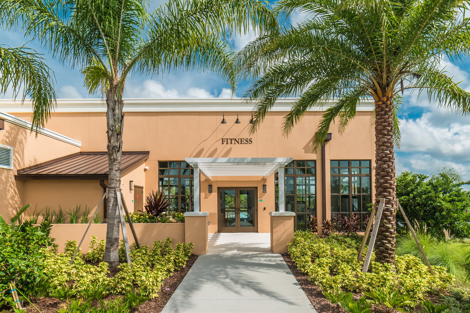 Entrance to the fitness center framed by palm trees and tropical landscaping.