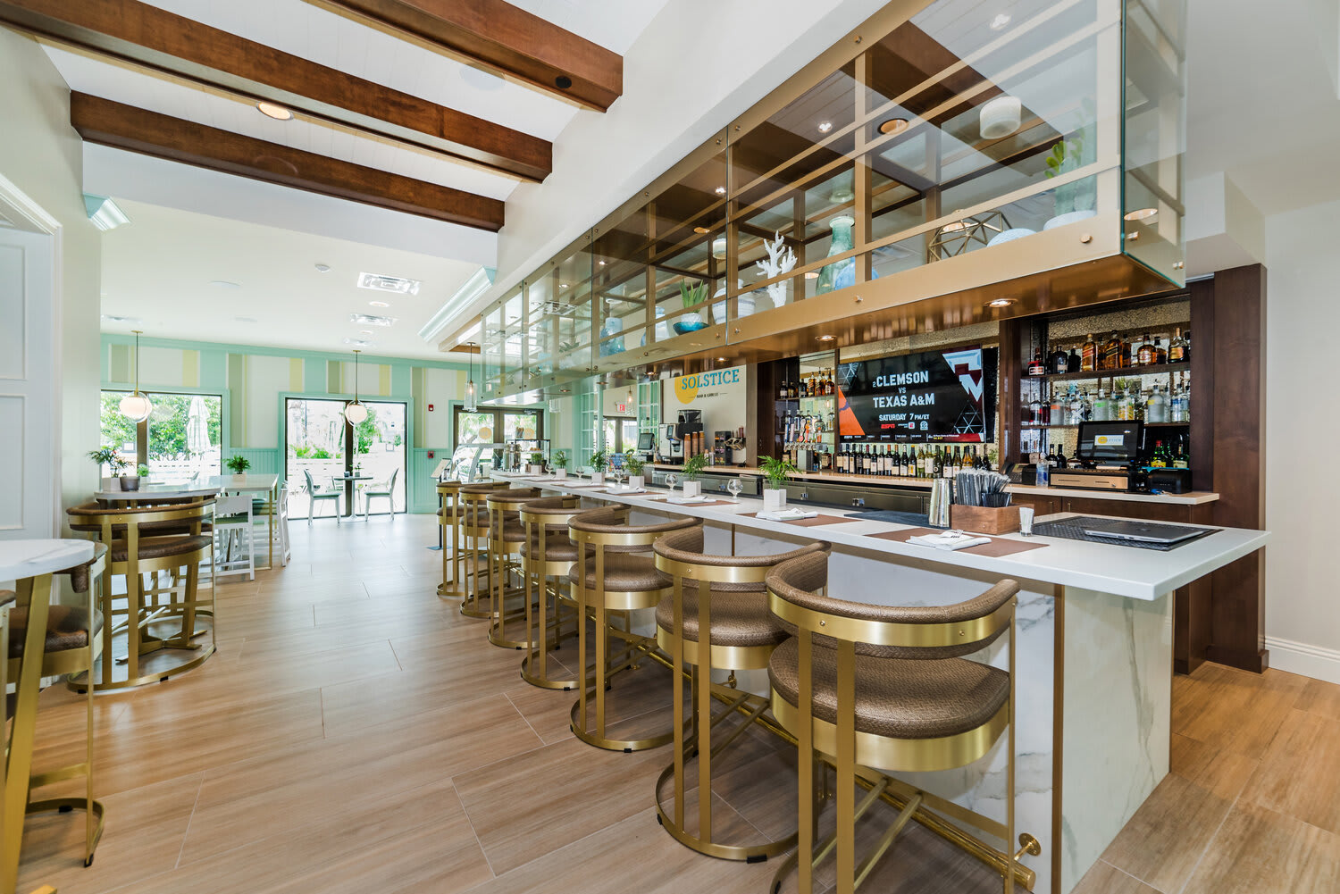 Modern bar area with gold-accented stools and a bright, open atmosphere.